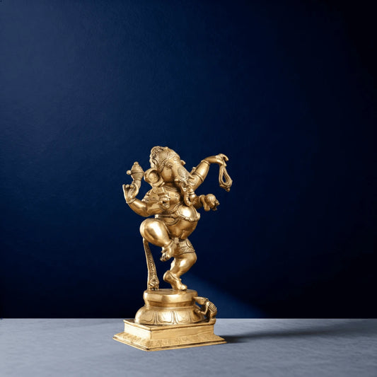 Side view of polished golden dancing Ganesha idol holding pasha and modak on ornate pedestal