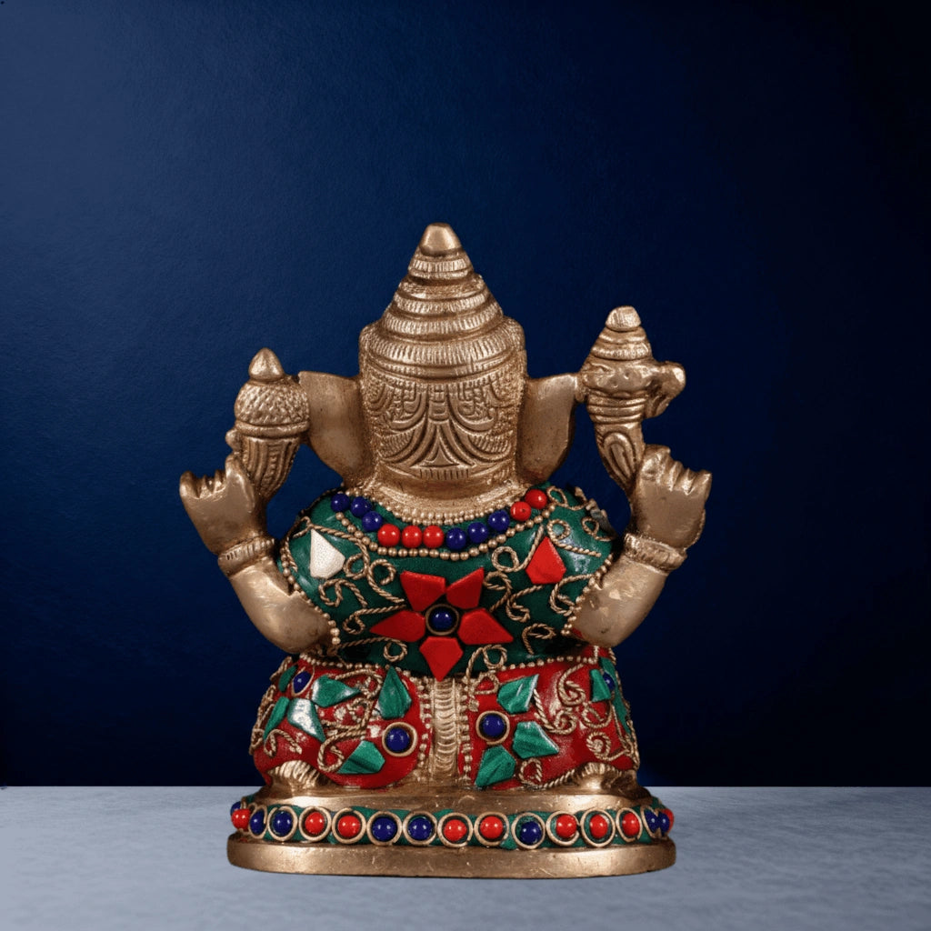 Back view of brass Ganesha idol decorated with red, green, and blue stones