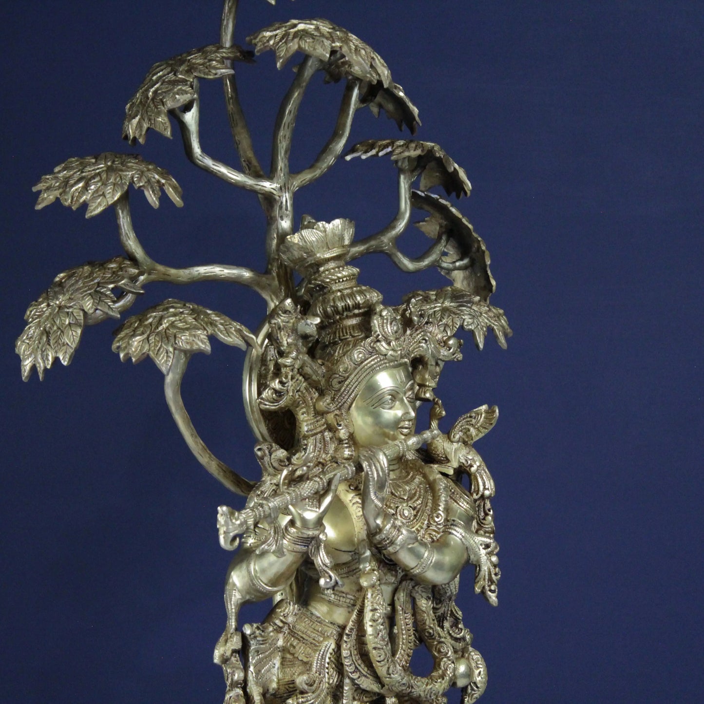 Decorative Brass metal Krishna sculpture with intricate designs on a blue background