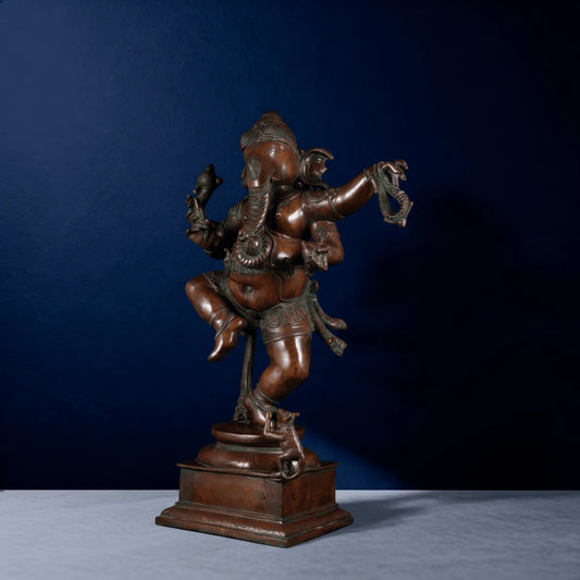 Angled front view of copper-toned Ganapati idol in dancing pose holding ankusa and pasha