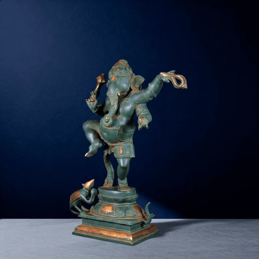 Angled view of green oxidized brass dancing Ganesha statue with raised arm and mouse figure on base