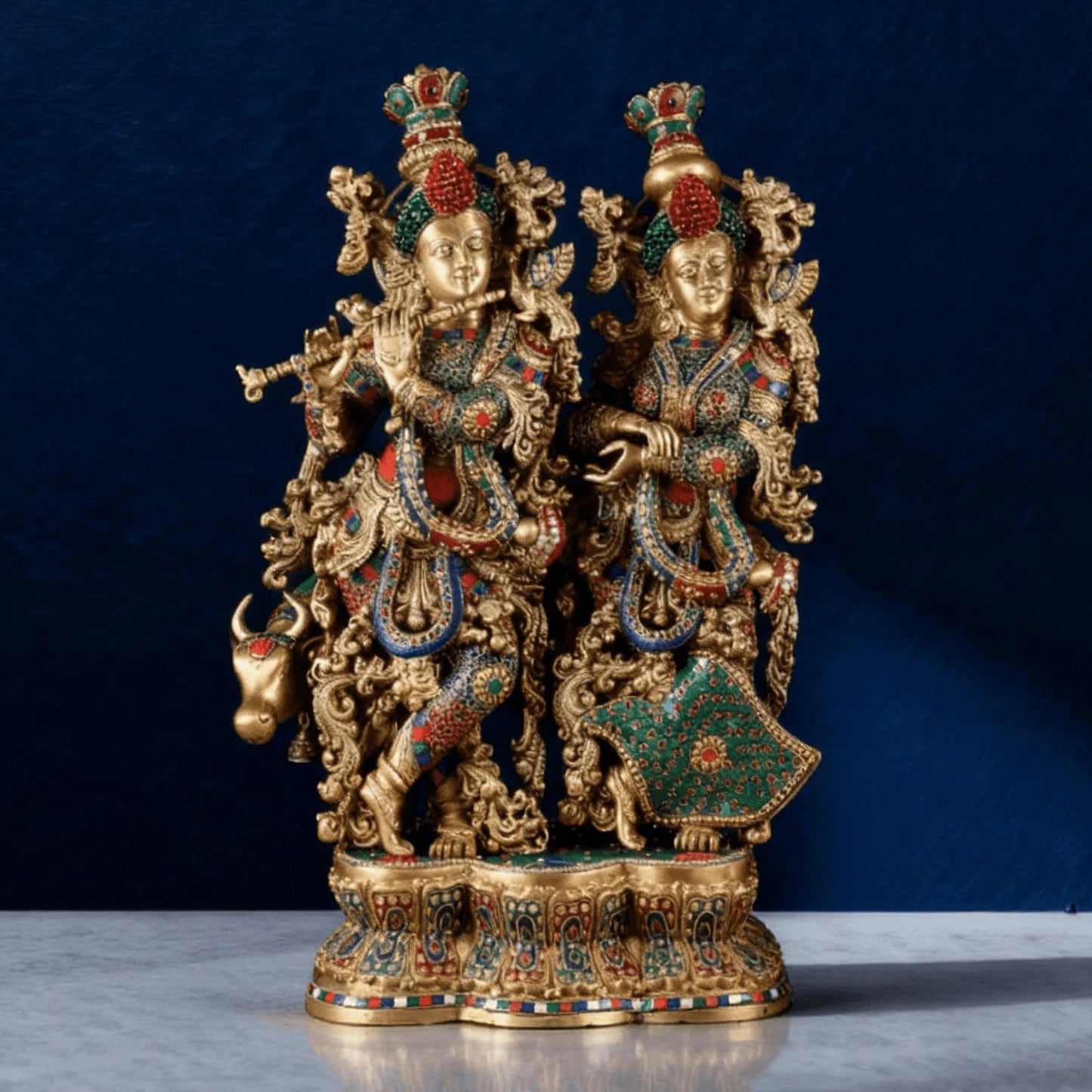 Front view of handcrafted brass Radha Krishna idol with cow, antique finish and multicolor inlay on detailed base.