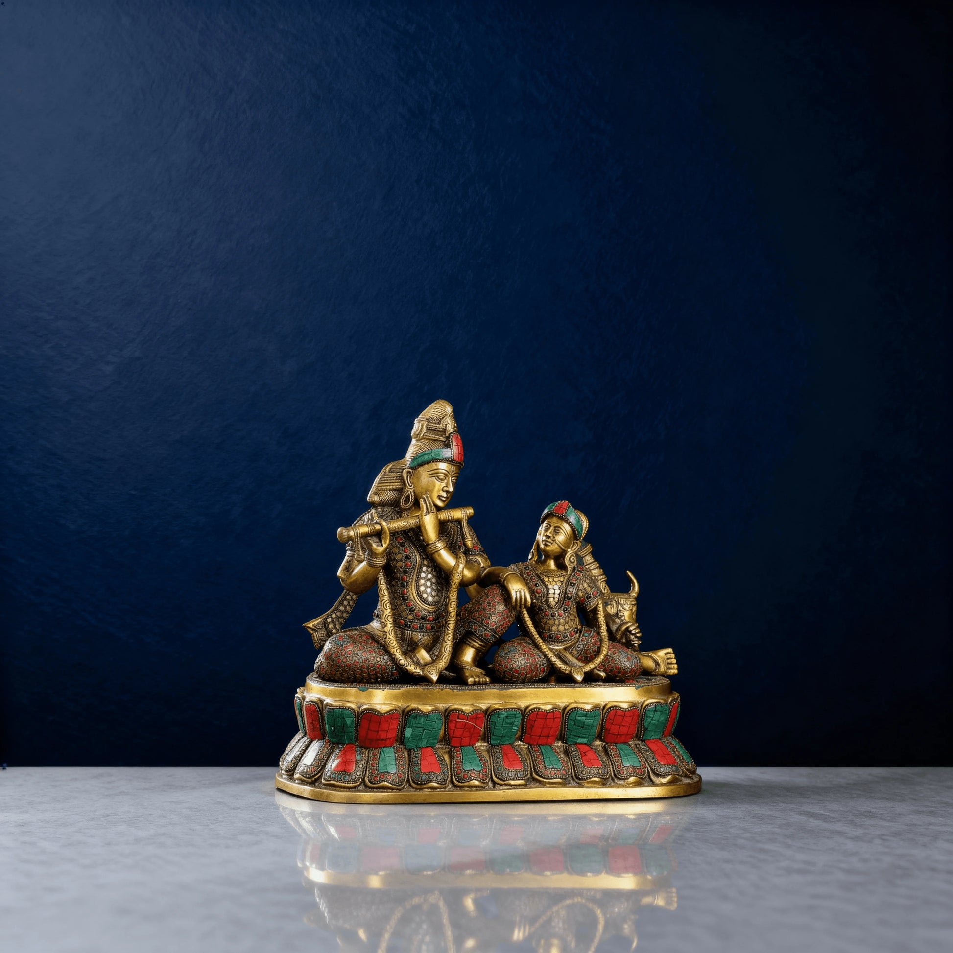 Front view of handcrafted brass Radha Krishna with cow, seated on stone-inlaid pedestal, 14-inch sculpture