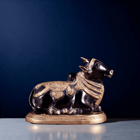 Black and gold brass Nandi idol placed on a marble surface with a dark blue backdrop