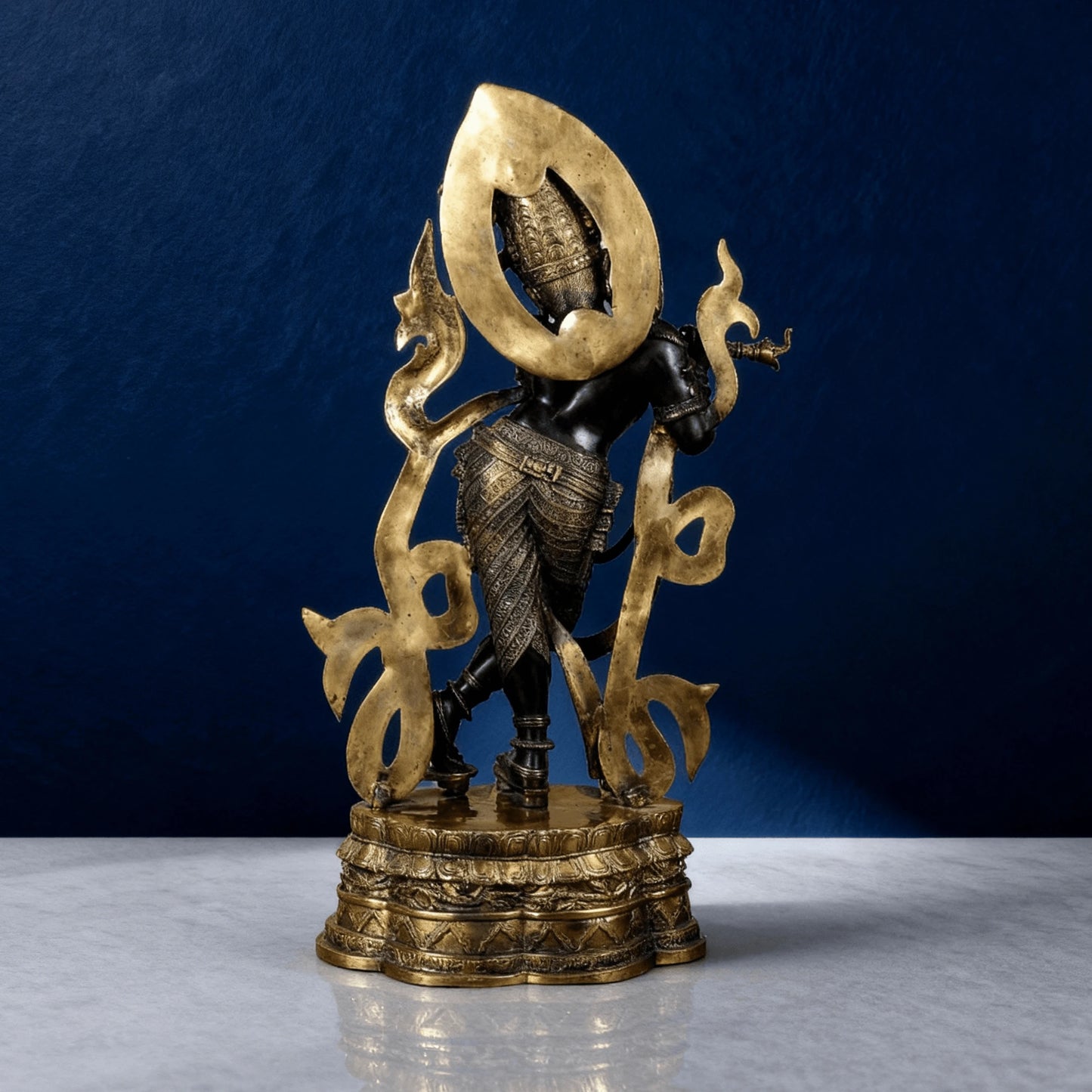 Handcrafted brass Krishna idol with antique black finish playing flute – front angle on marble surface