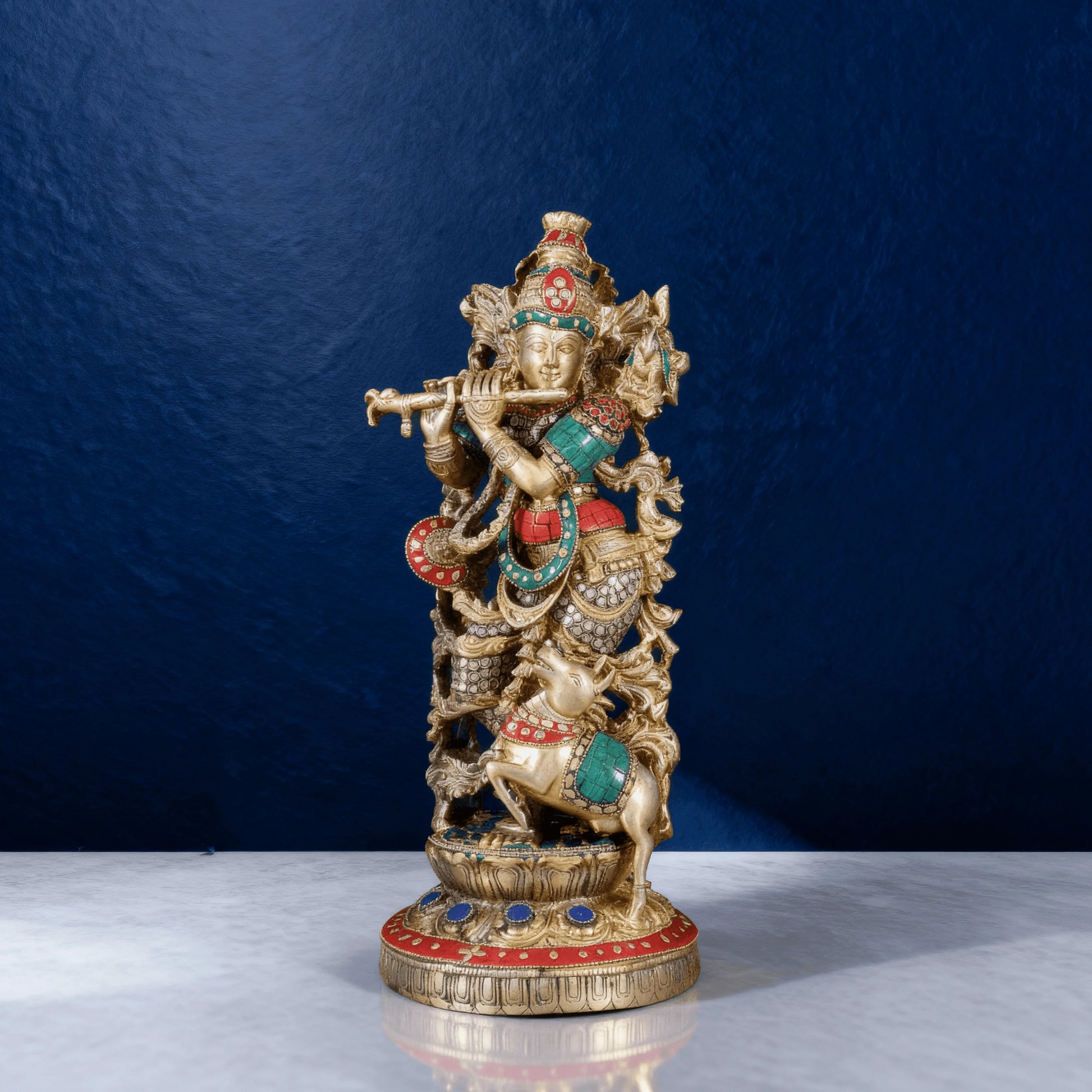 Intricately handcrafted brass Lord Krishna statue with flute and jumping cow, detailed in green, red and blue enamel work – front angle