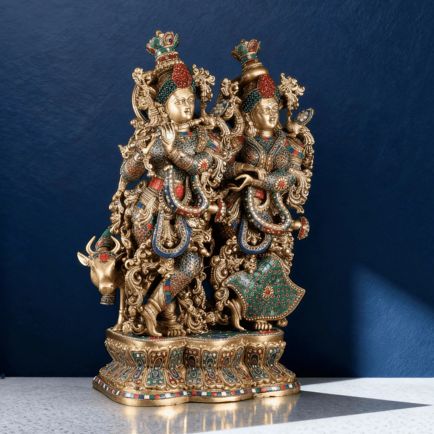 Angled side view of solid brass Radha Krishna with cow idol, intricate detailing and colorful hand-applied accents.
