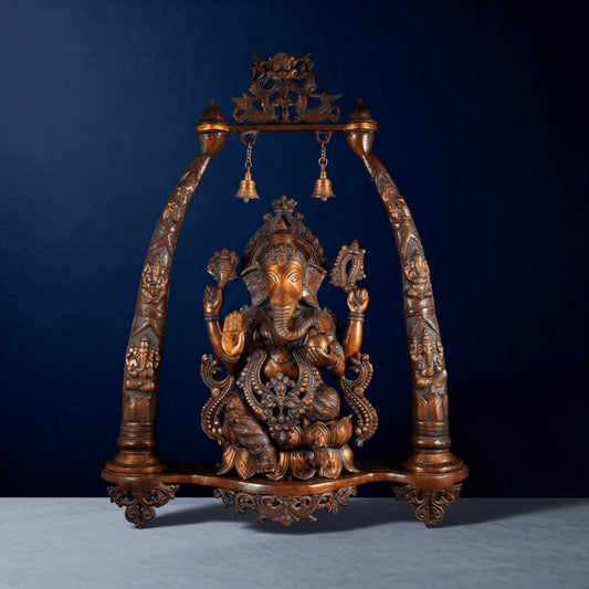 Handcrafted brass Ganesha swing idol with detailed carvings on a dark blue studio background