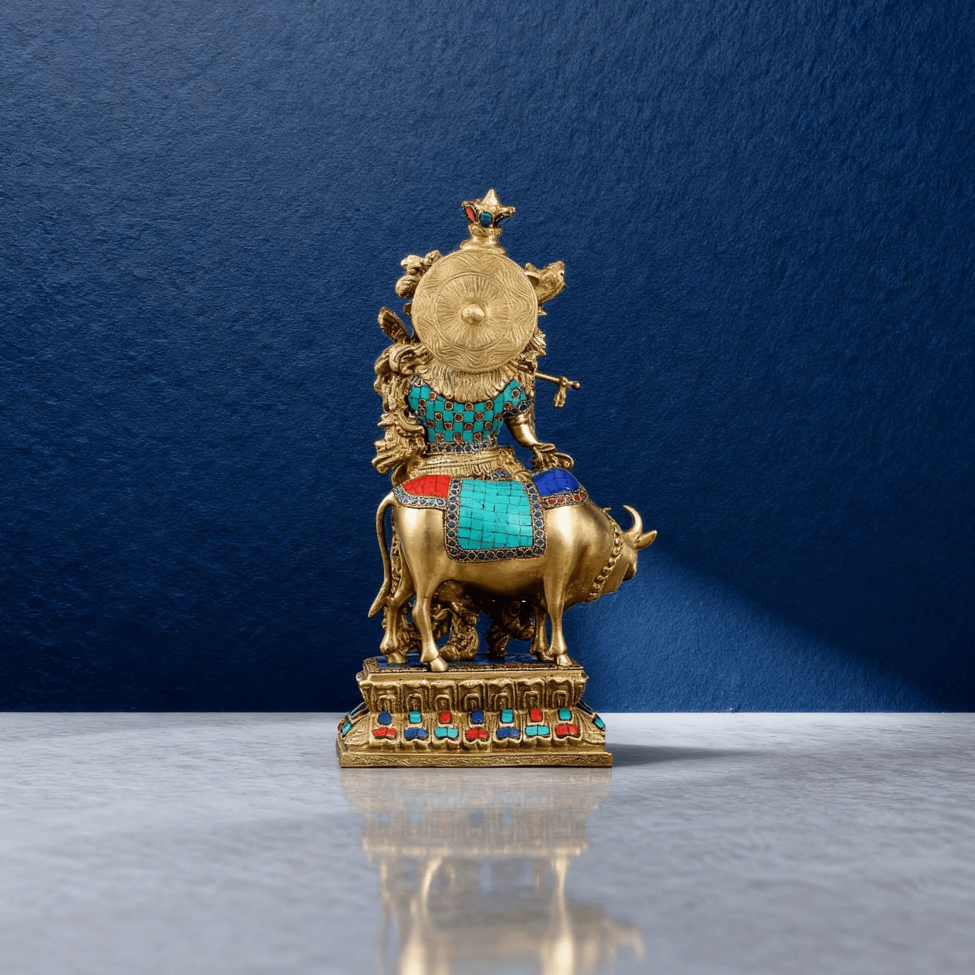 Rear view of handcrafted brass Krishna with cow statue, antique finish with turquoise and red stone inlay on ornate base