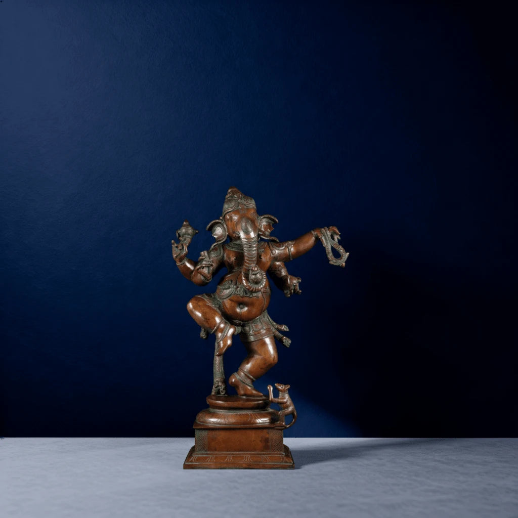 Straight-on shot of reddish bronze Ganesha sculpture with raised leg and ornate pedestal design
