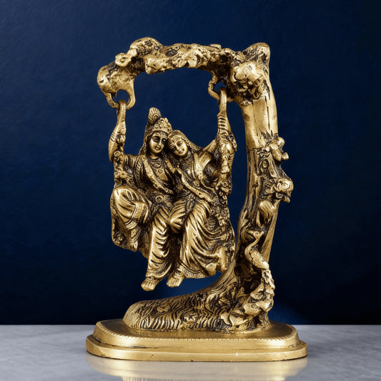 Handcrafted brass Radha Krishna jhula statue with ornate tree arch and detailed carving, perfect for spiritual home decor.