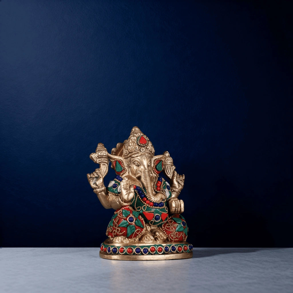 Brass Ganesha idol with multicolor stonework on a blue studio background