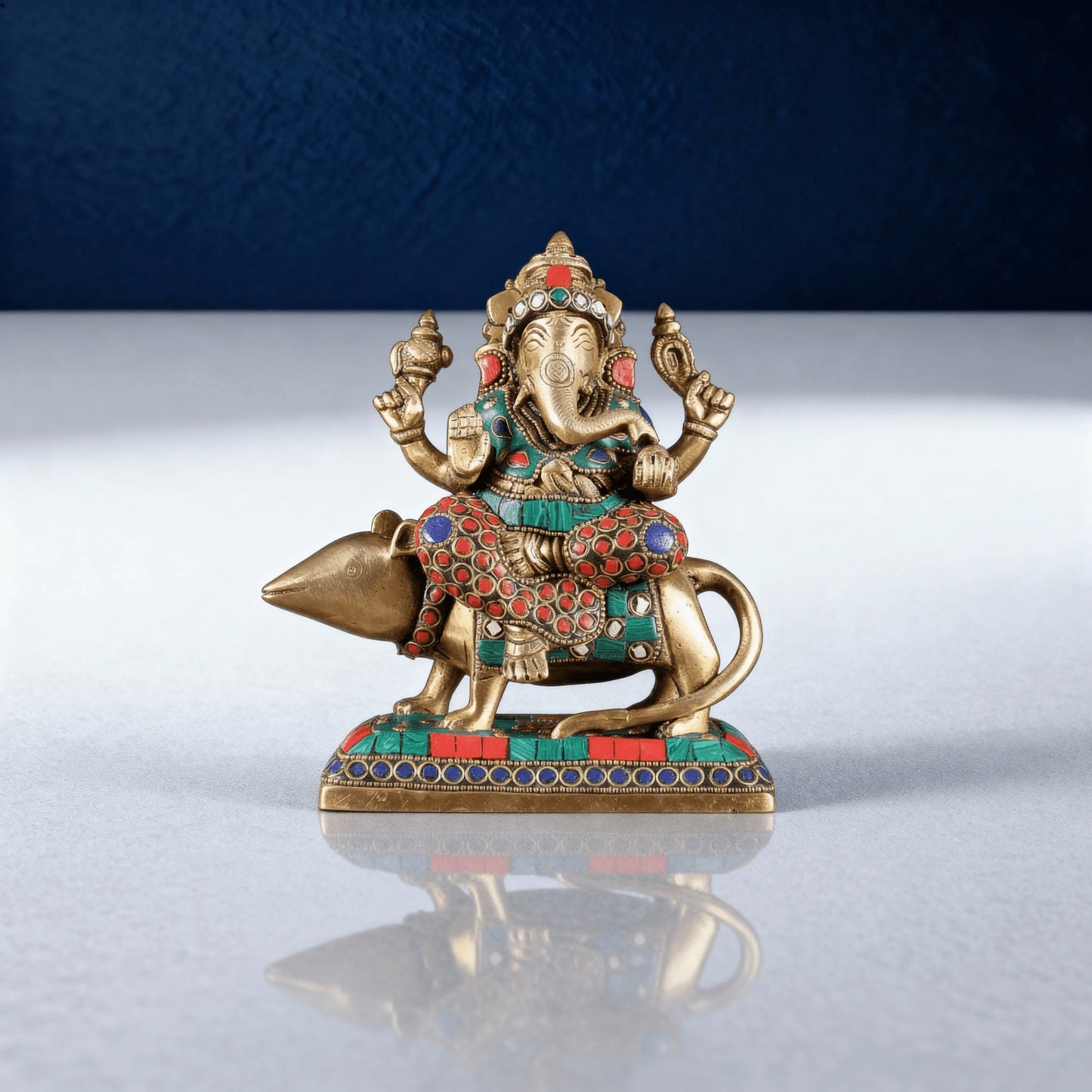 Decorative brass Ganesha murti seated on mouse with gemstone work centered front view
