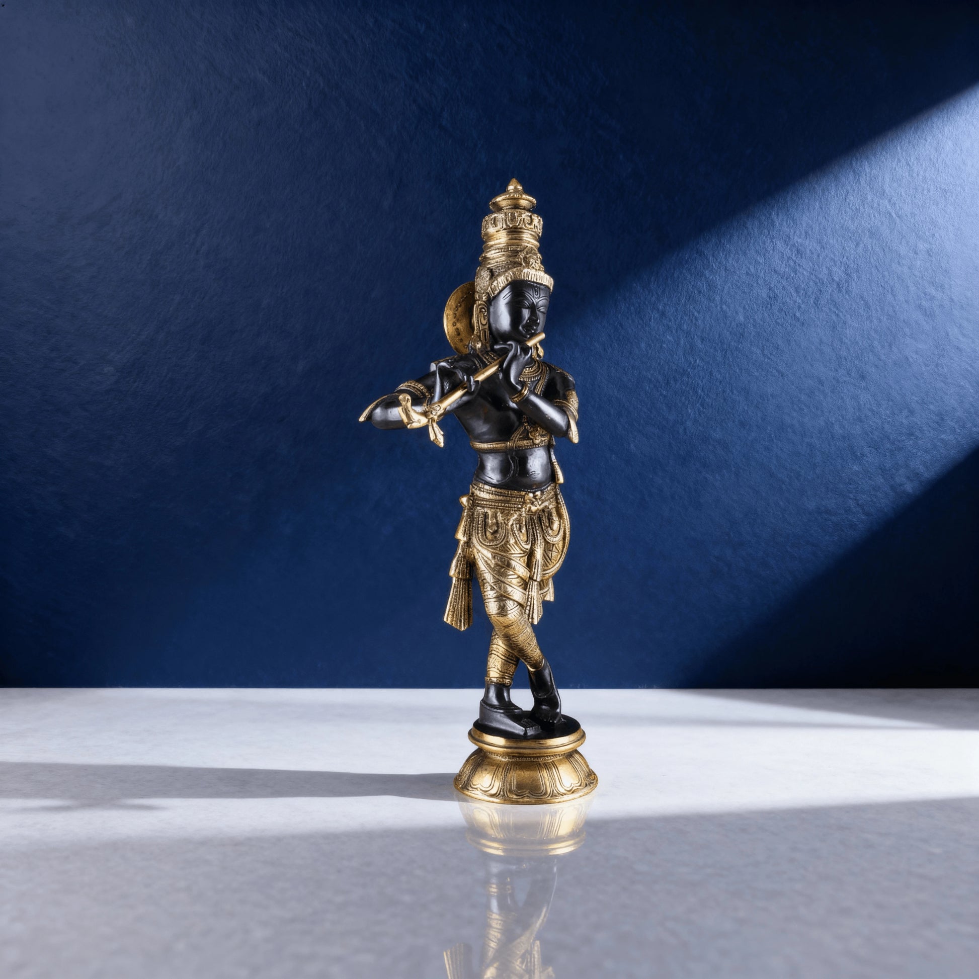 Brass black Krishna statue playing flute with intricate detailing on marble base