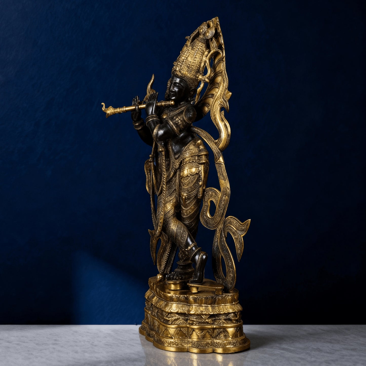 Elegant brass Krishna idol with ornate base and flowing detailing – rear view studio shot