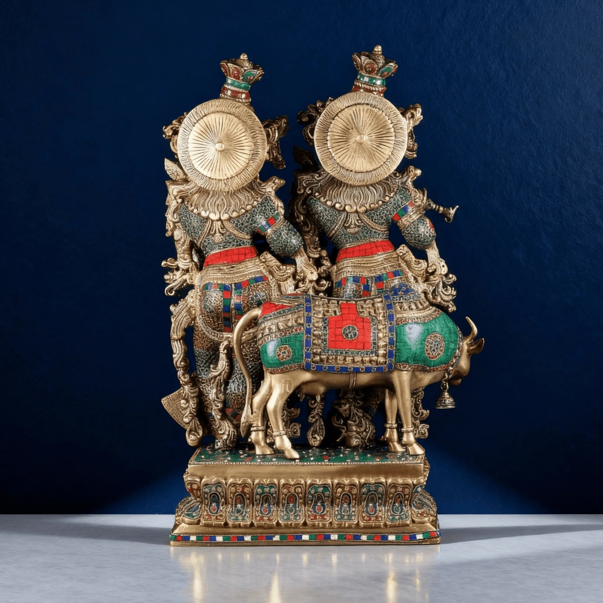 Back view of brass Radha Krishna idol and cow, showcasing detailed carvings and colorful enamel inlay work.
