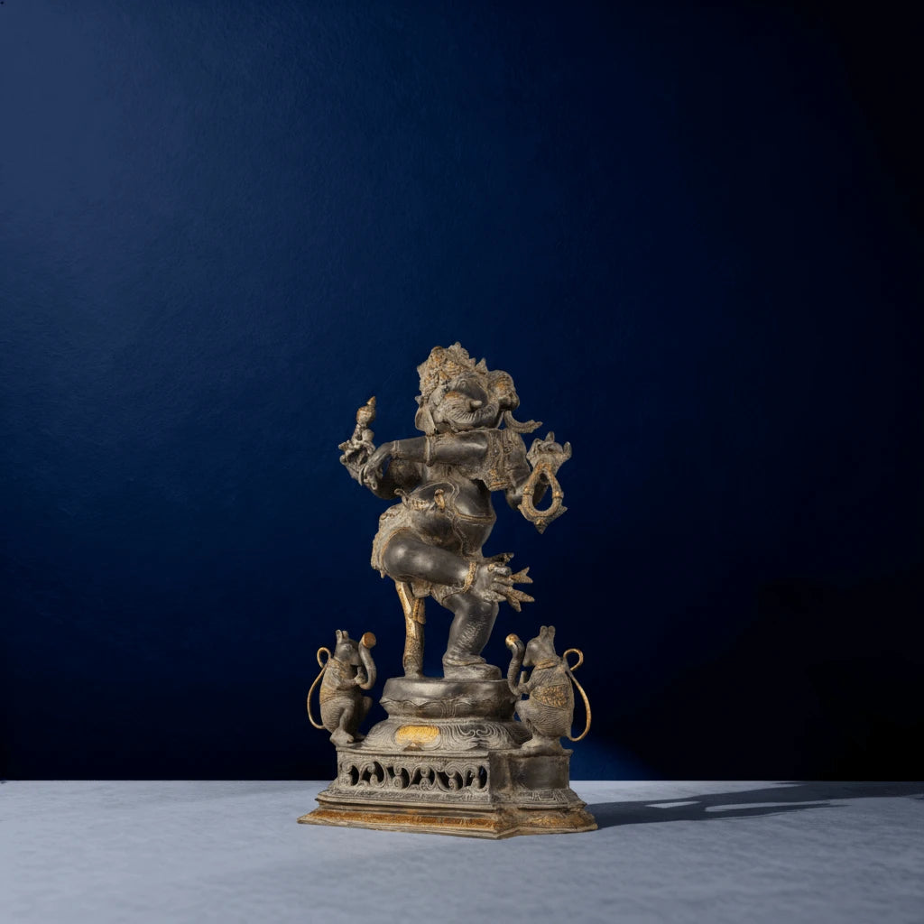 Side view of traditional metallic dancing Ganapati murti with decorative base and twin rodents