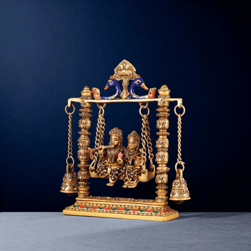 Side view of brass Radha Krishna swing idol with colorful meenakari accents, ornate pillars, chains and handcrafted detailing