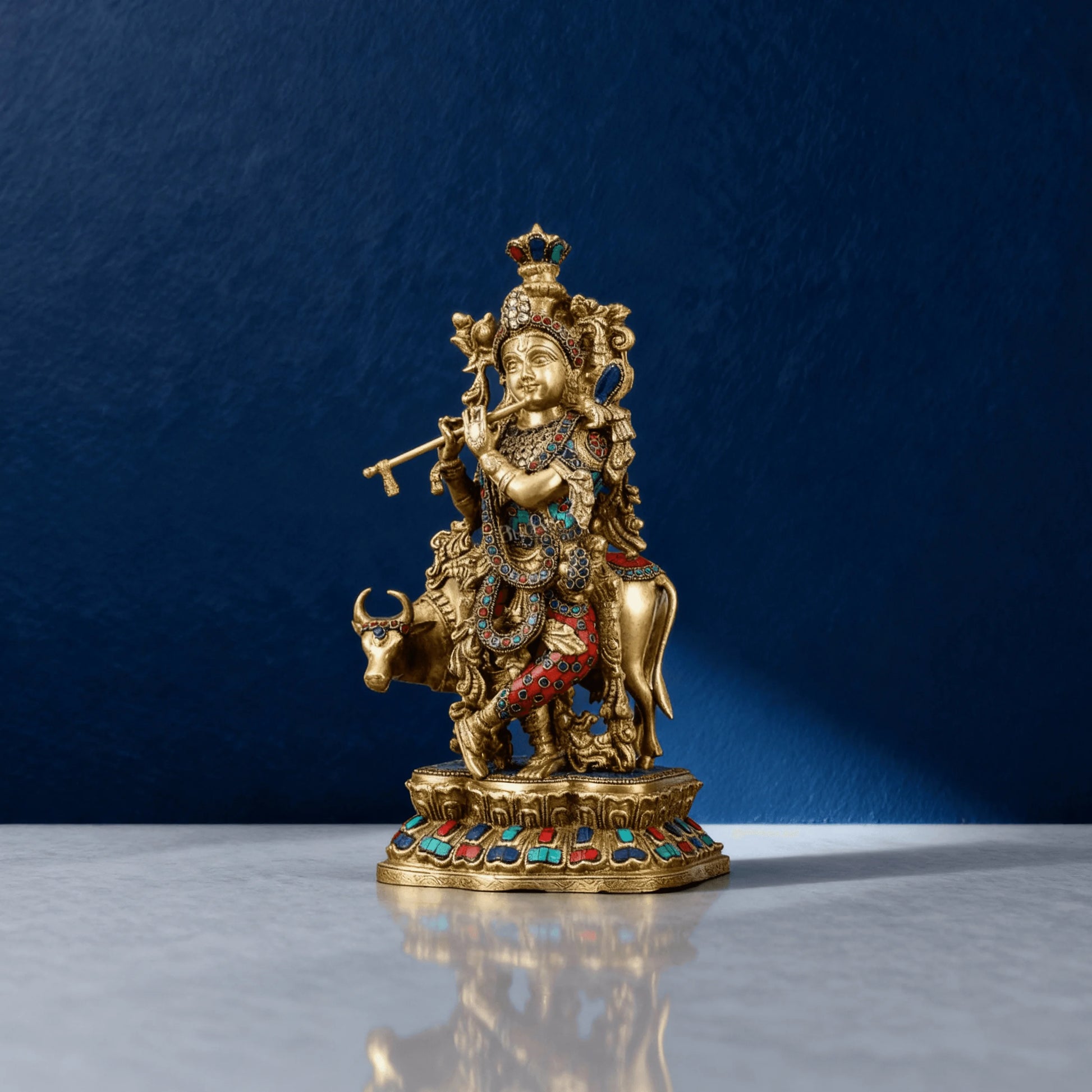 Front angle of 17-inch brass Krishna statue playing flute beside cow, detailed with red, blue stones and antique finish