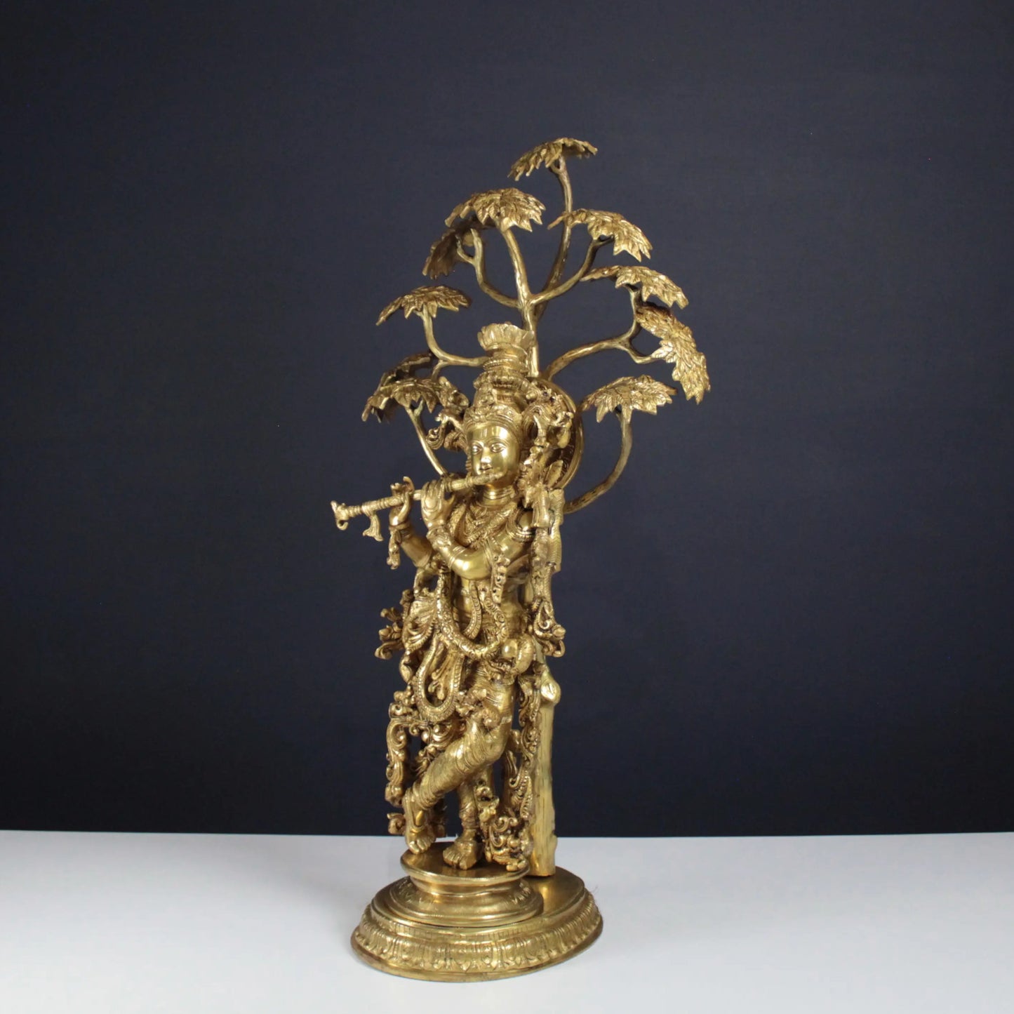 Gold decorative Krishna Idol on a white table with a dark background