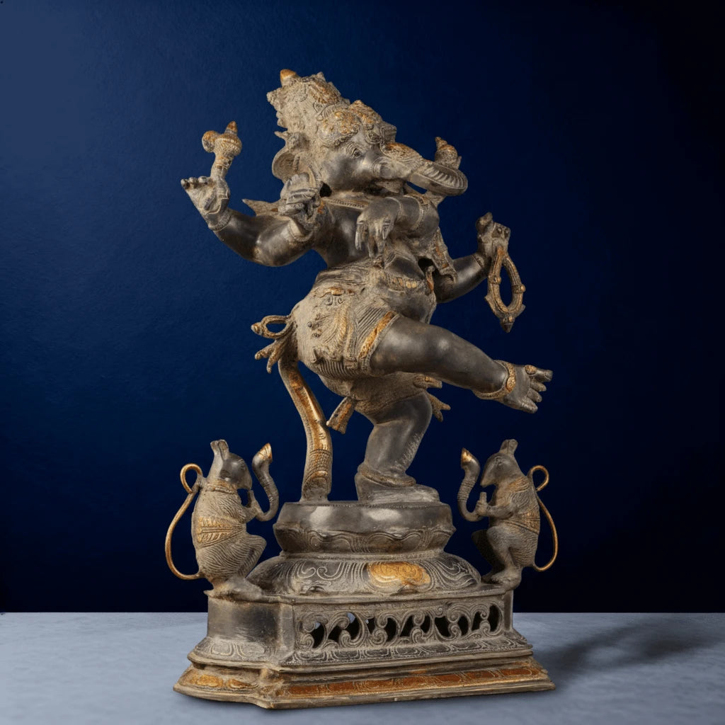 Angled close-up of intricately carved silver Ganesha idol with raised leg and golden highlights