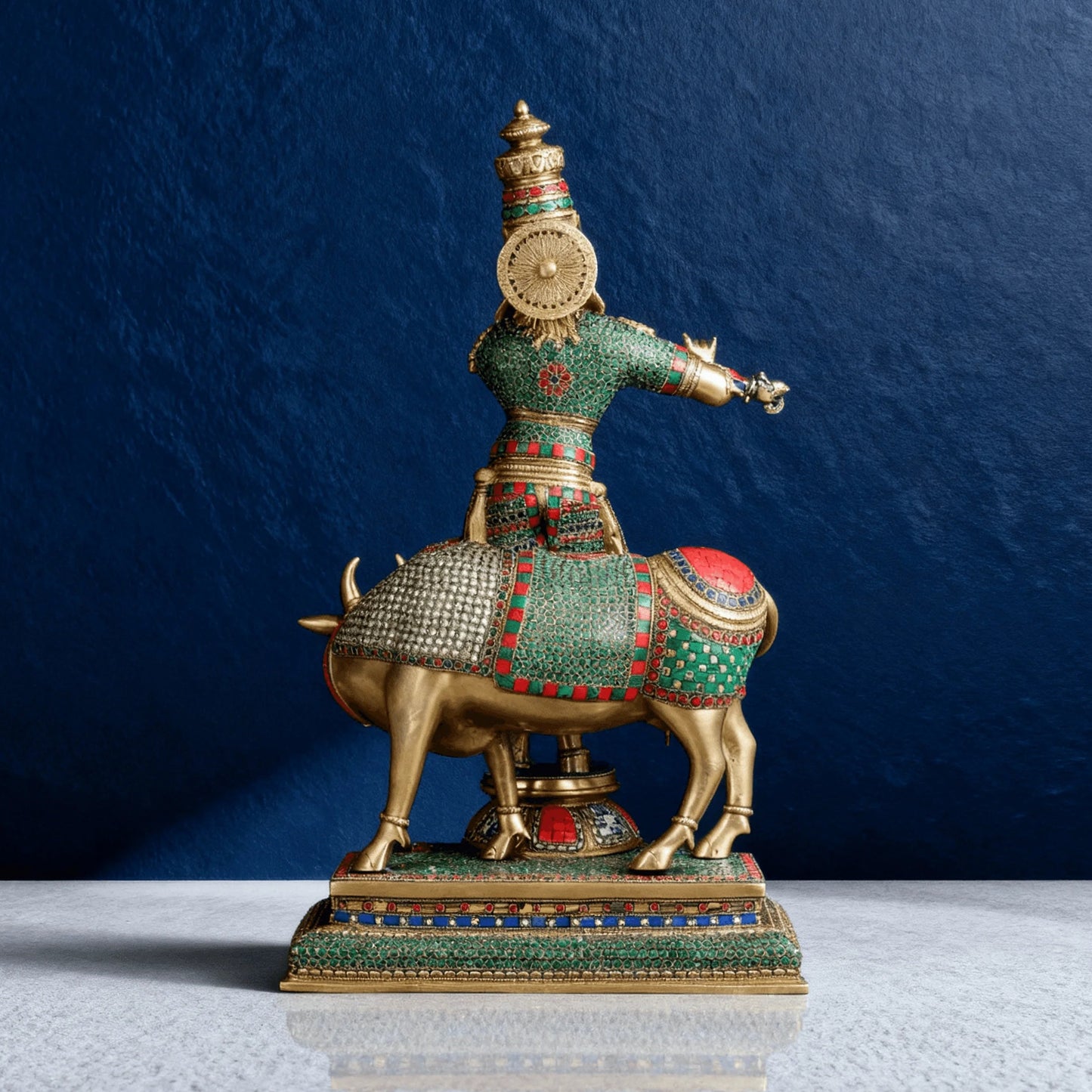 Back view of Krishna brass statue with cow, showing detailed meenakari and textured craftsmanship on base and attire