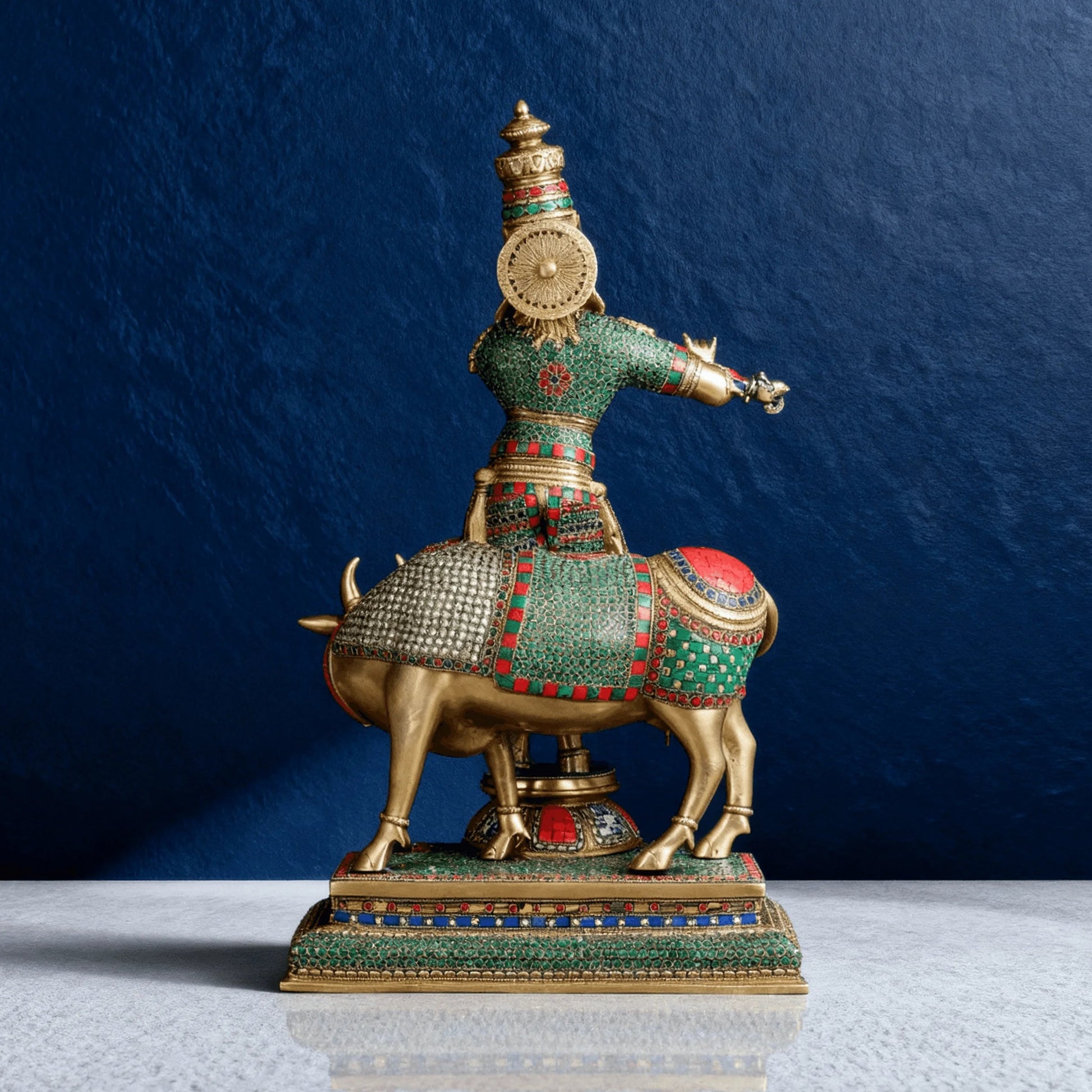 Back view of Krishna brass statue with cow, showing detailed meenakari and textured craftsmanship on base and attire