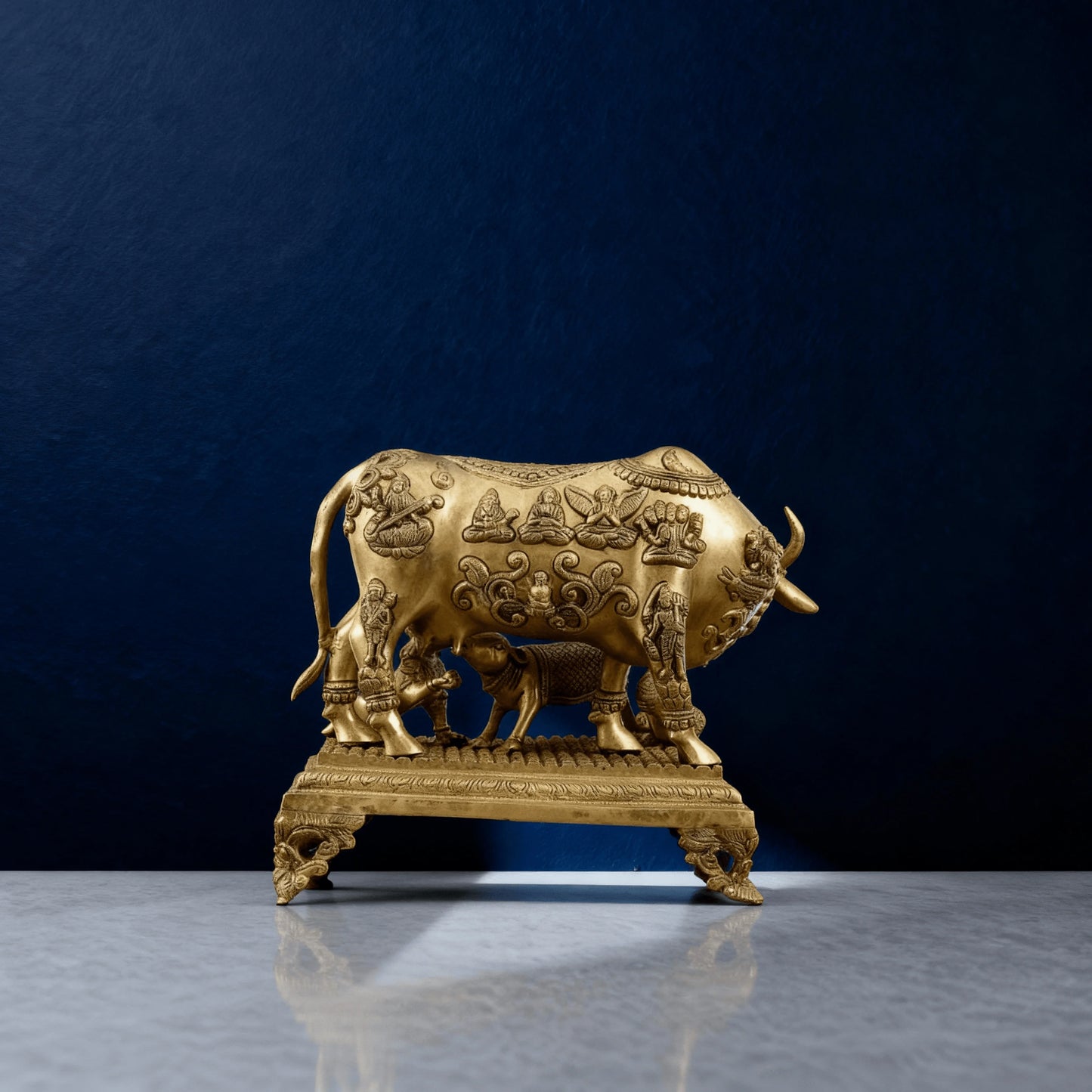 Rear angle of brass Kamadhenu idol showing embossed deities and detailed legwork on decorative base