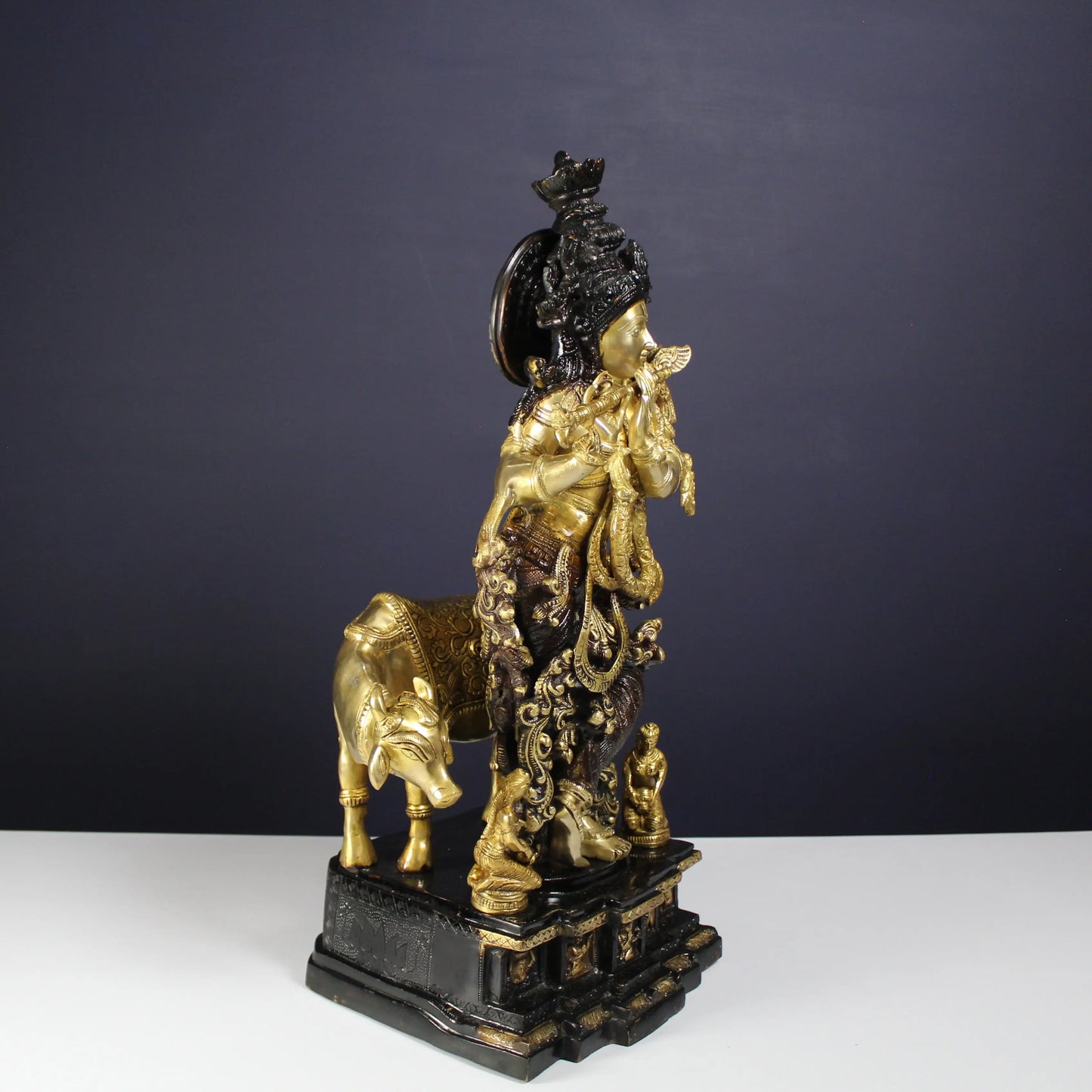 Decorative Krishna Idol with gold and black finish on a dark background
