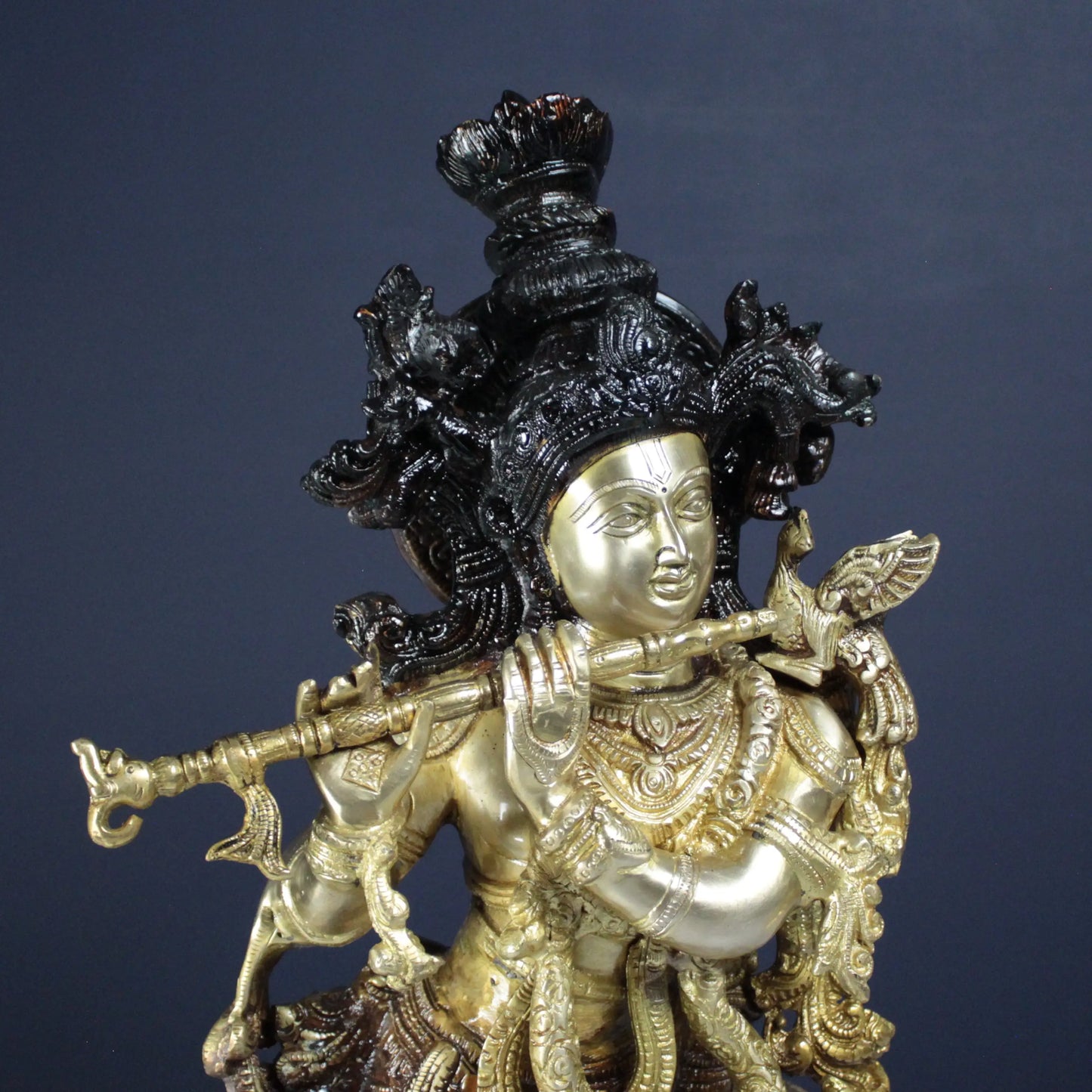 Decorative Krishna statue with intricate details on a dark background