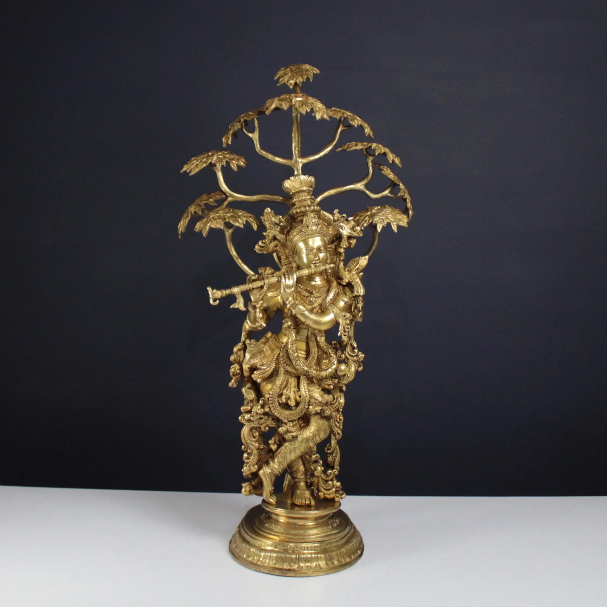 Gold-coloured decorative Krishna statue with intricate designs on a black background