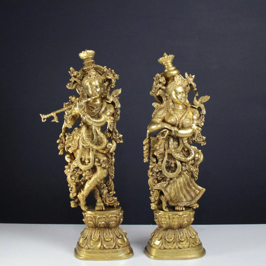 Two Radha Krishna gold statues on a dark background