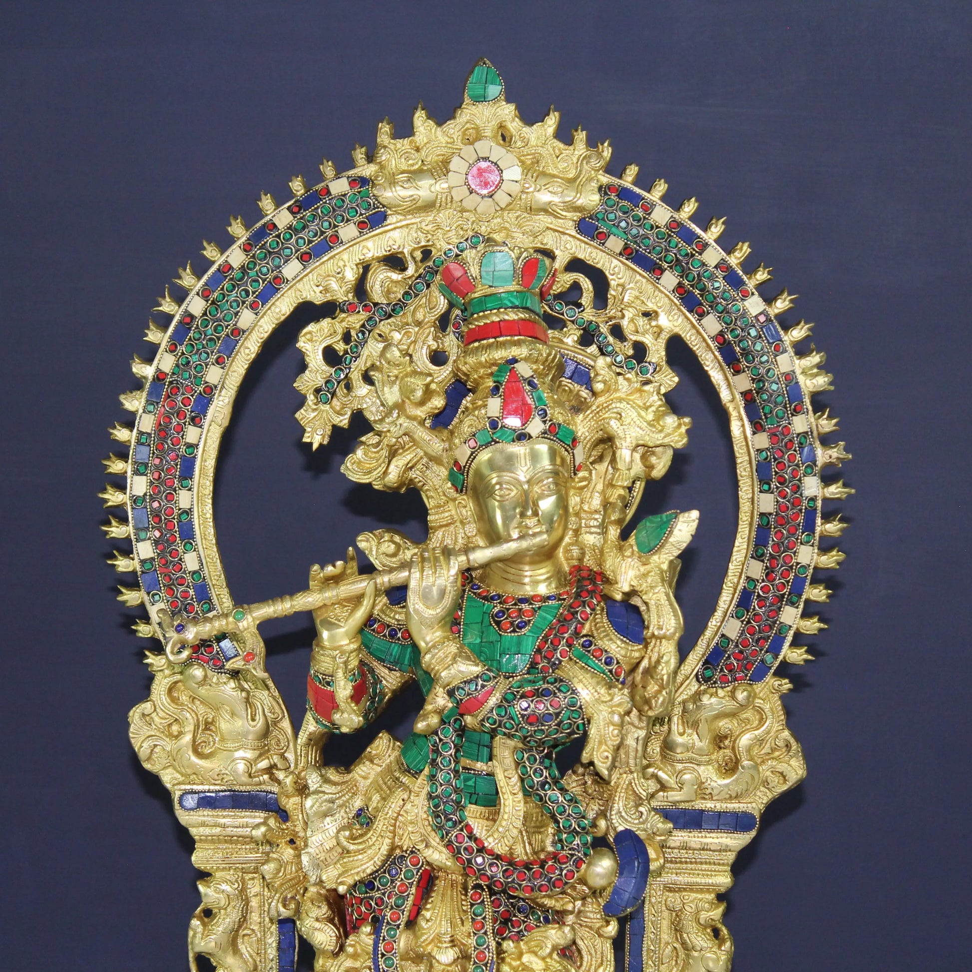 Decorative Krishna gold and gemstone statue on a dark blue background