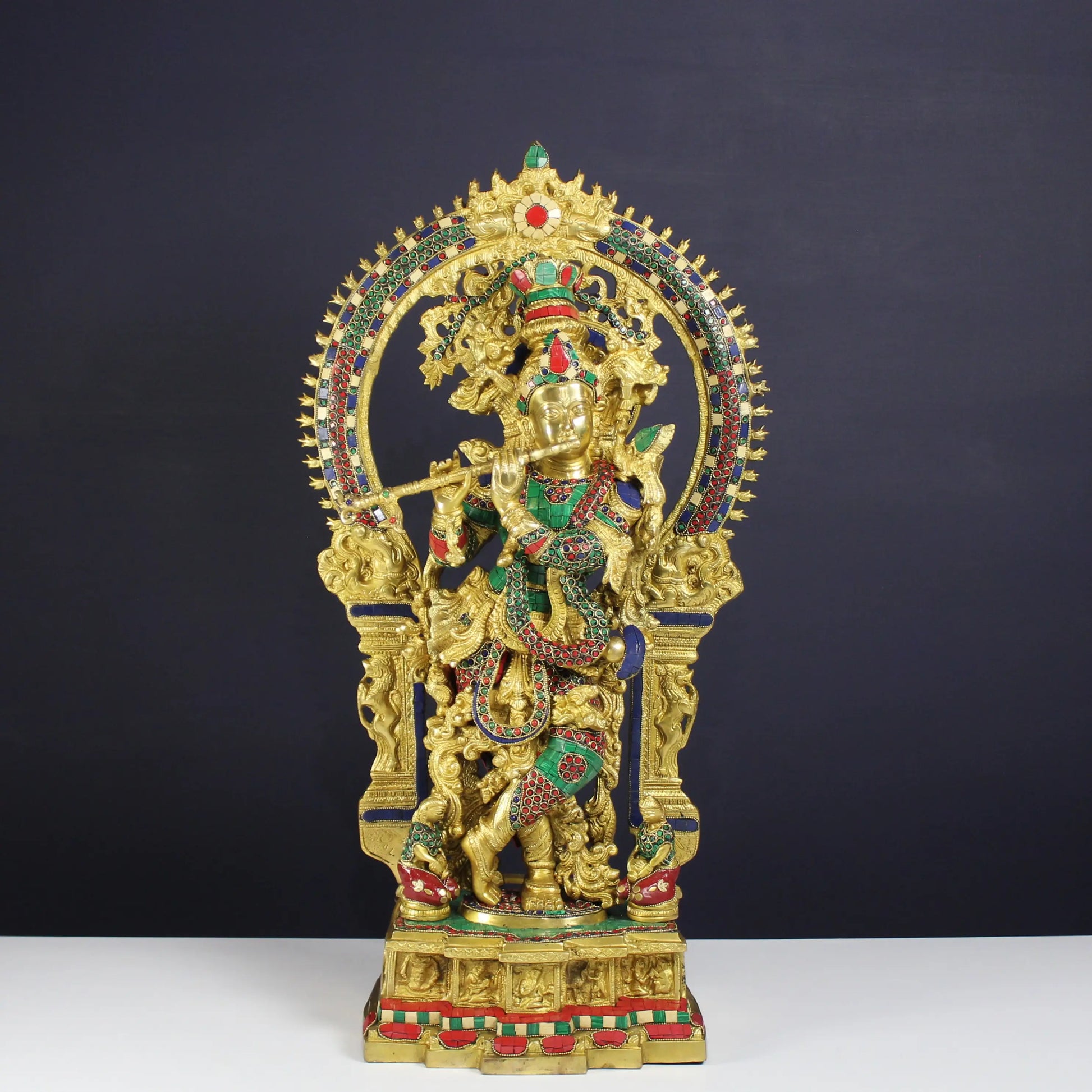 Krishnan statue with minakari on a dark background