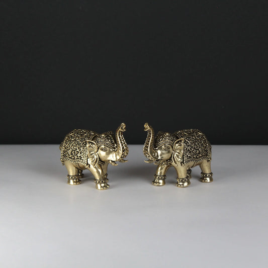 Two ornate gold elephant figurines on a white surface with a black background