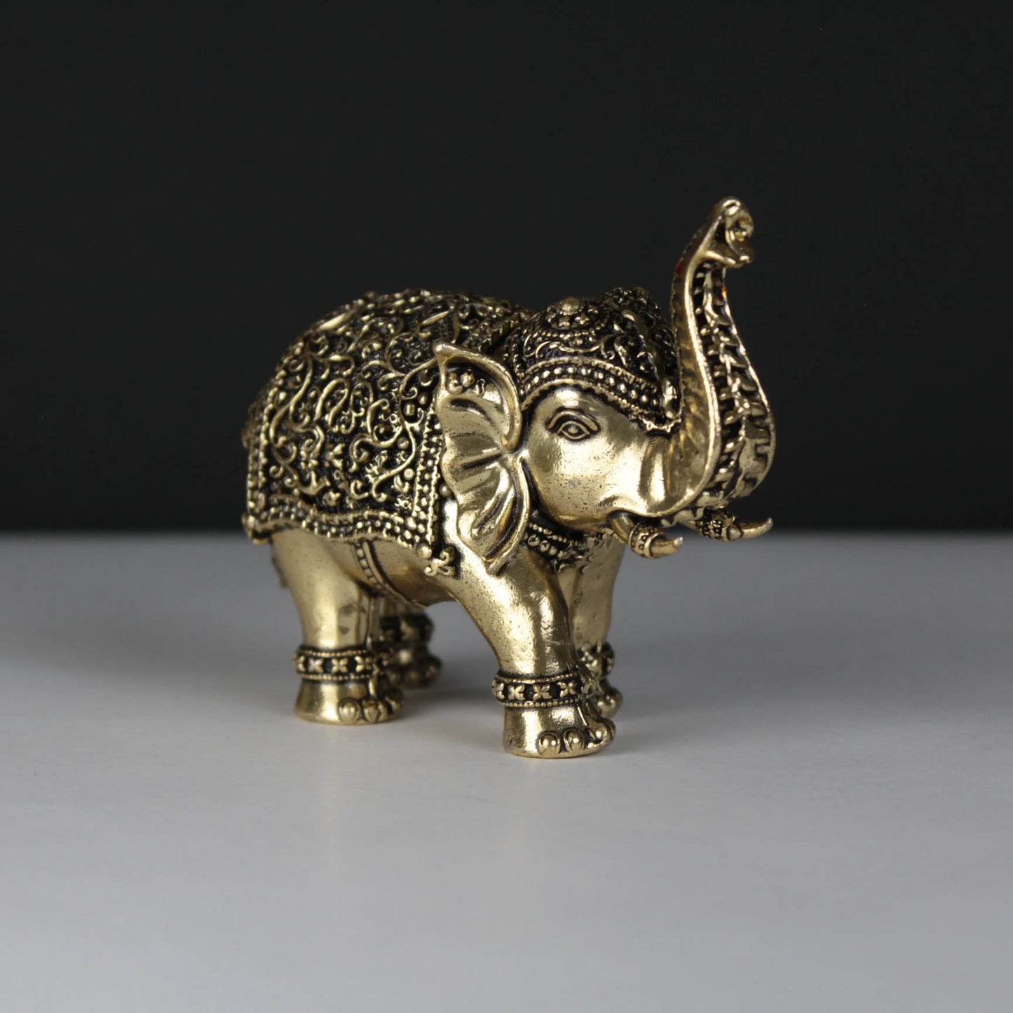 Decorative brass elephant figure on a dark background