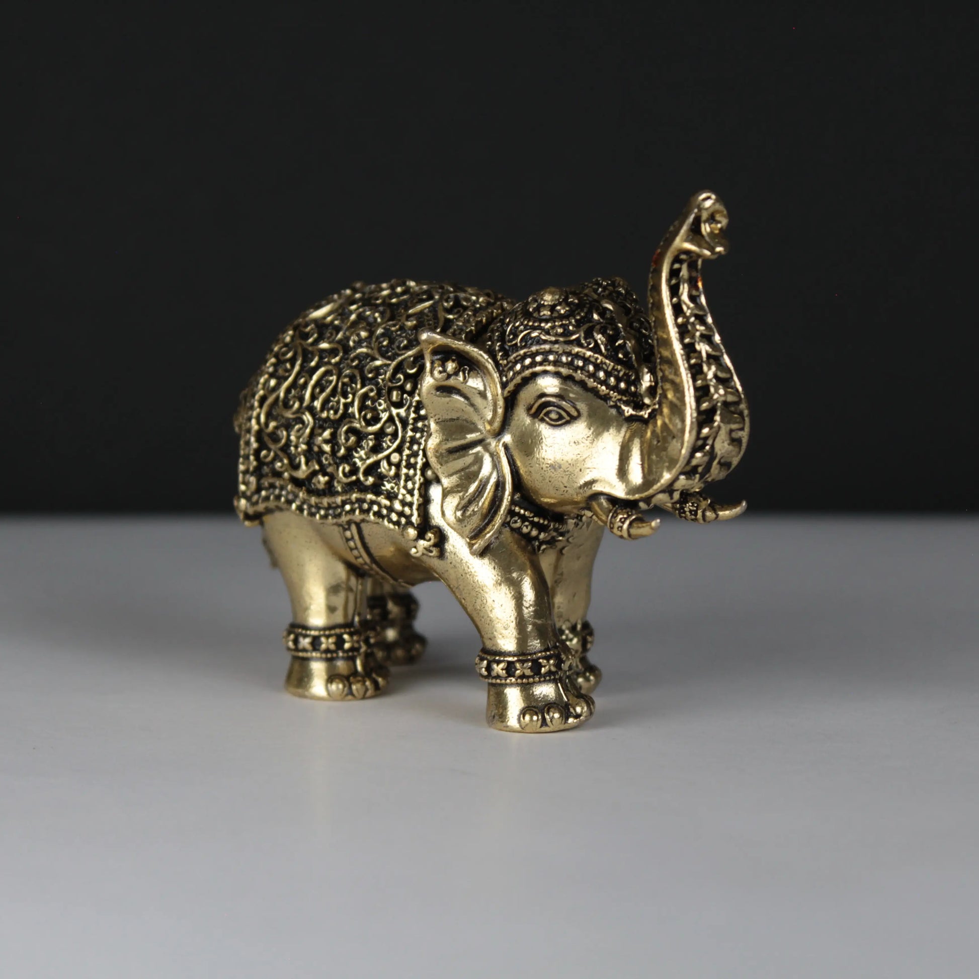 Decorative brass elephant figure on a dark background
