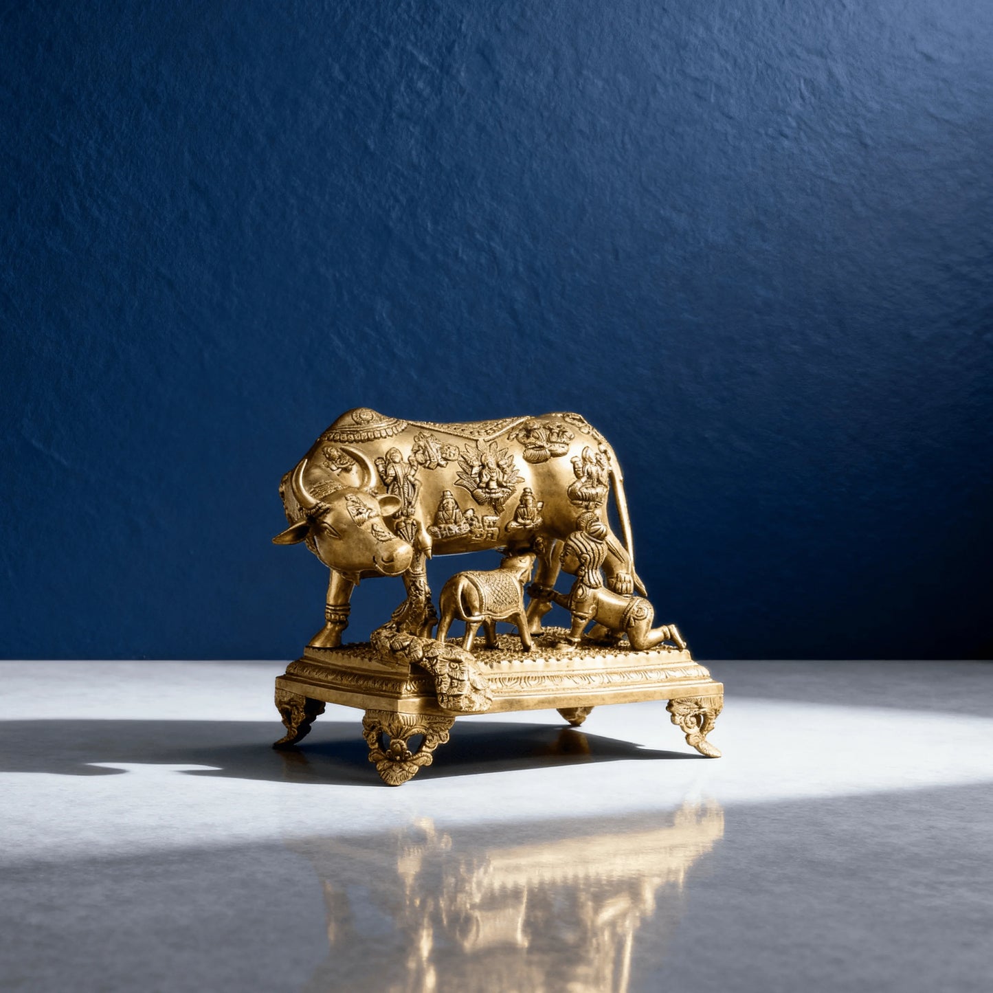 Premium brass Kamadhenu idol on sculpted base with polished antique finish, angled view