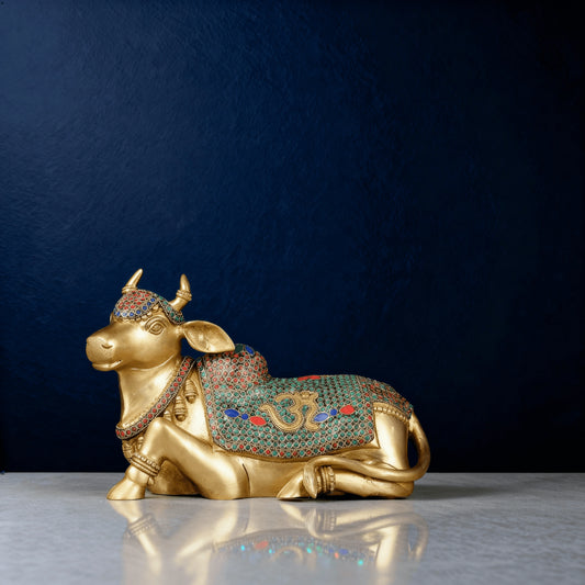 brass Nandi sculpture with colorful stonework and Om carving on the back, captured on a reflective marble surface