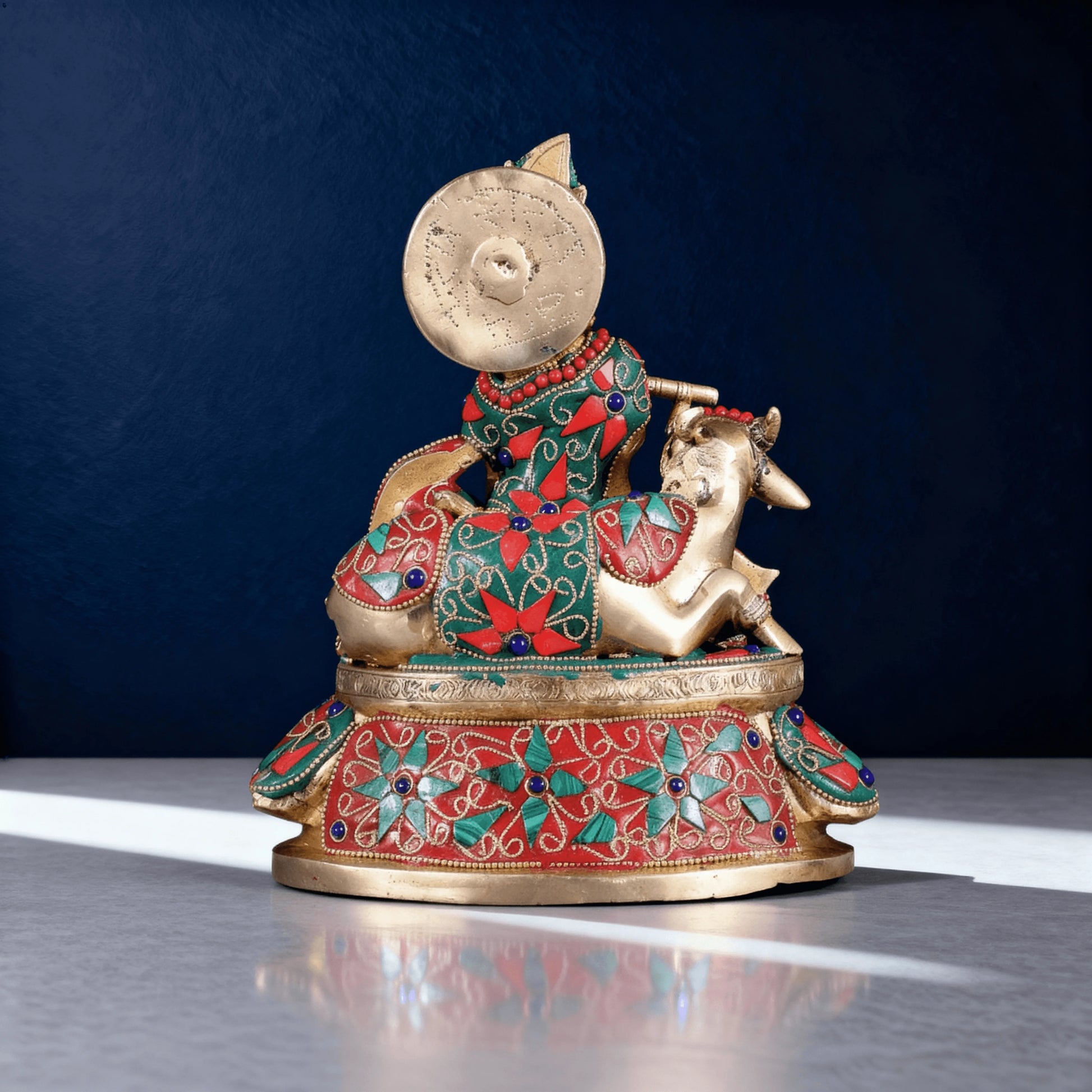 Rear angle of meenakari brass Krishna statue showing intricate patterns on cow and back of figure.
