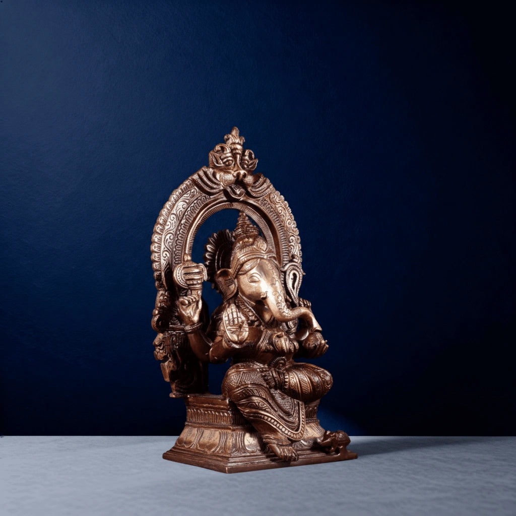 Left Side-angle view of brass Ganesha statue seated under ornate arch with detailed carvings for home decor