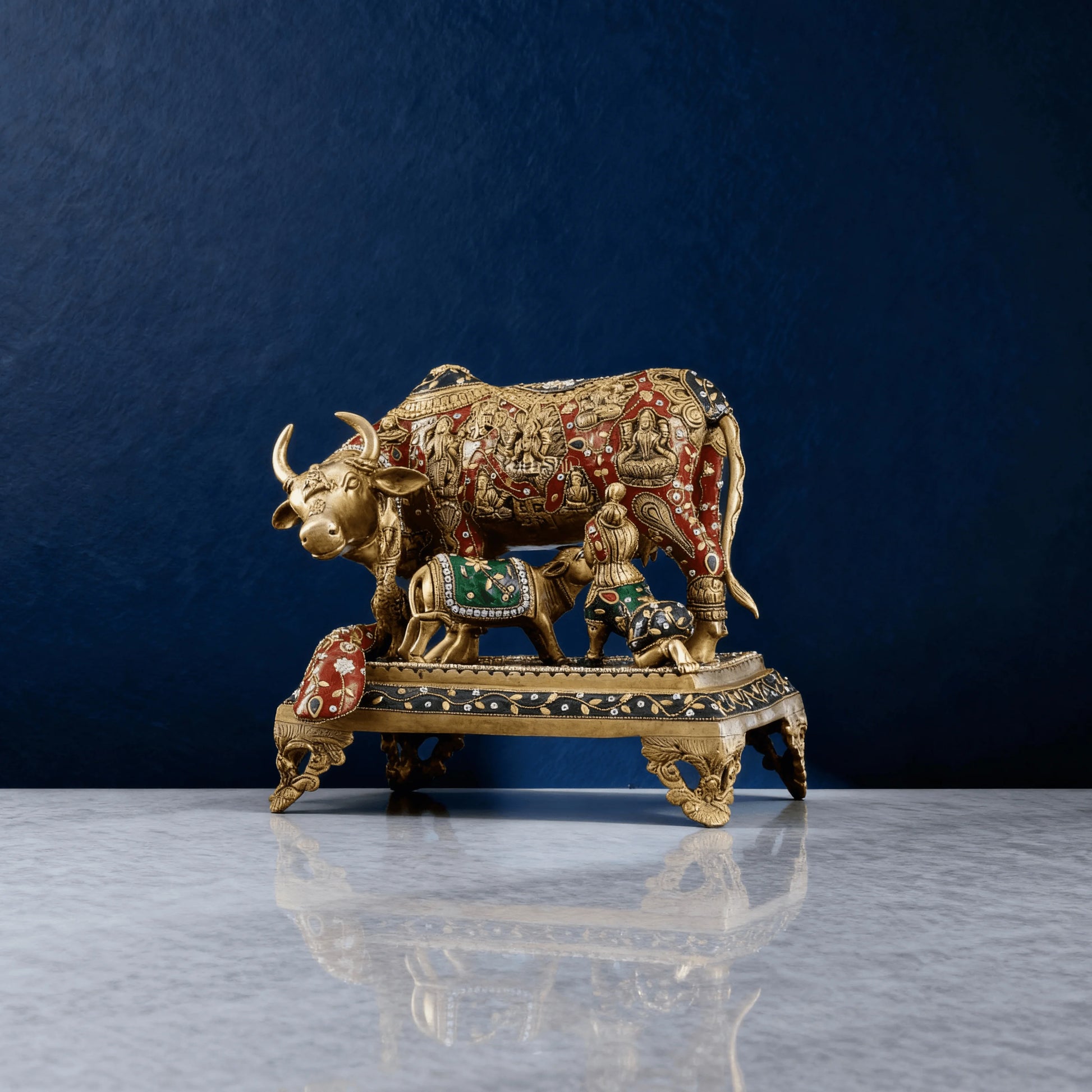 Full view of 14-inch Kamadhenu brass statue on ornate base, with calf and peacock, red and green accents