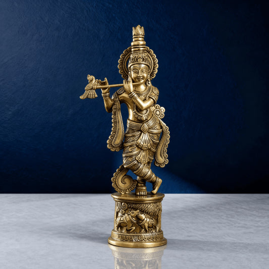 Pure brass Lord Krishna idol playing flute, detailed traditional carvings and golden finish, photographed on marble with dark blue premium backdrop.