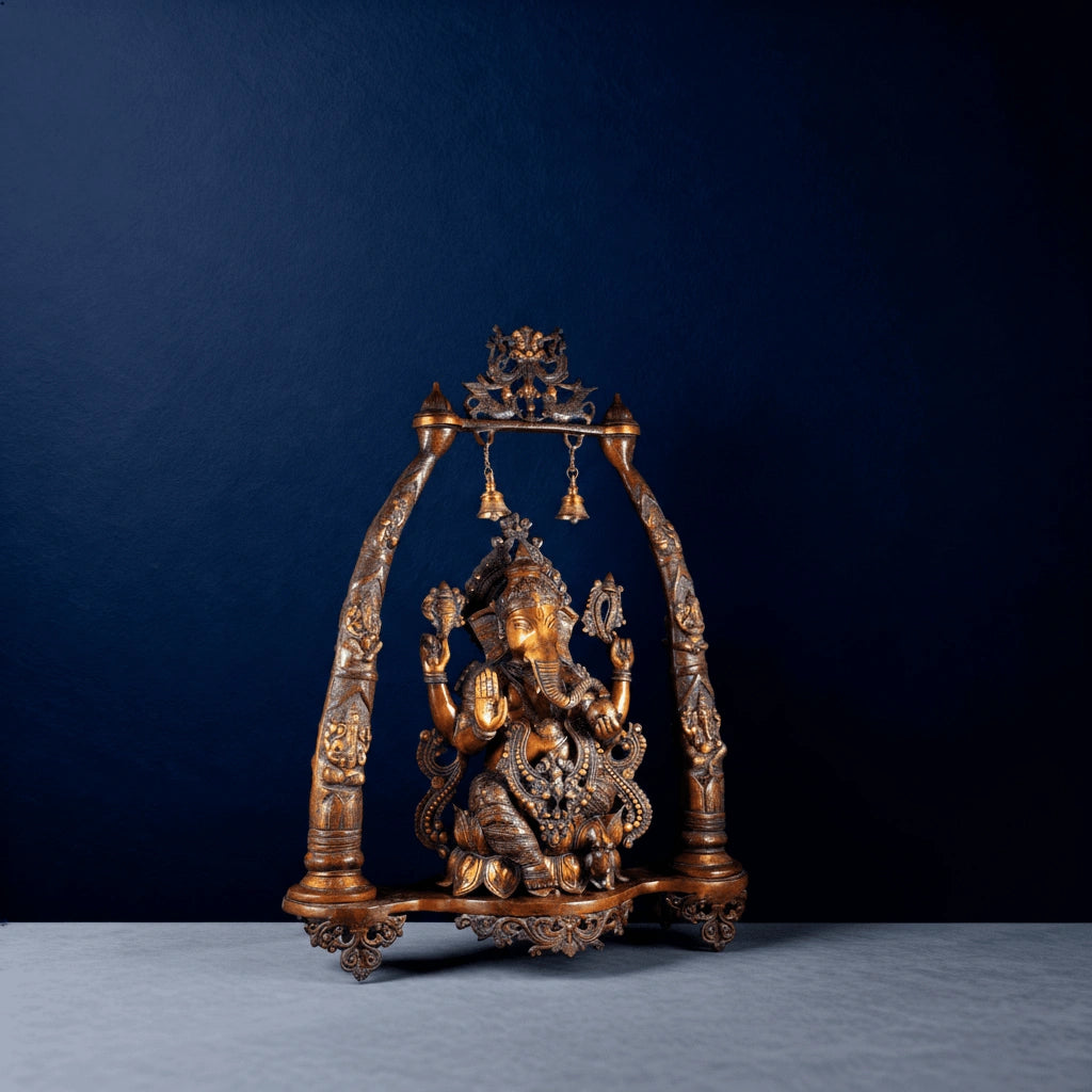 Front view of brass Ganesha swing idol with decorative arch and hanging bells in studio lighting