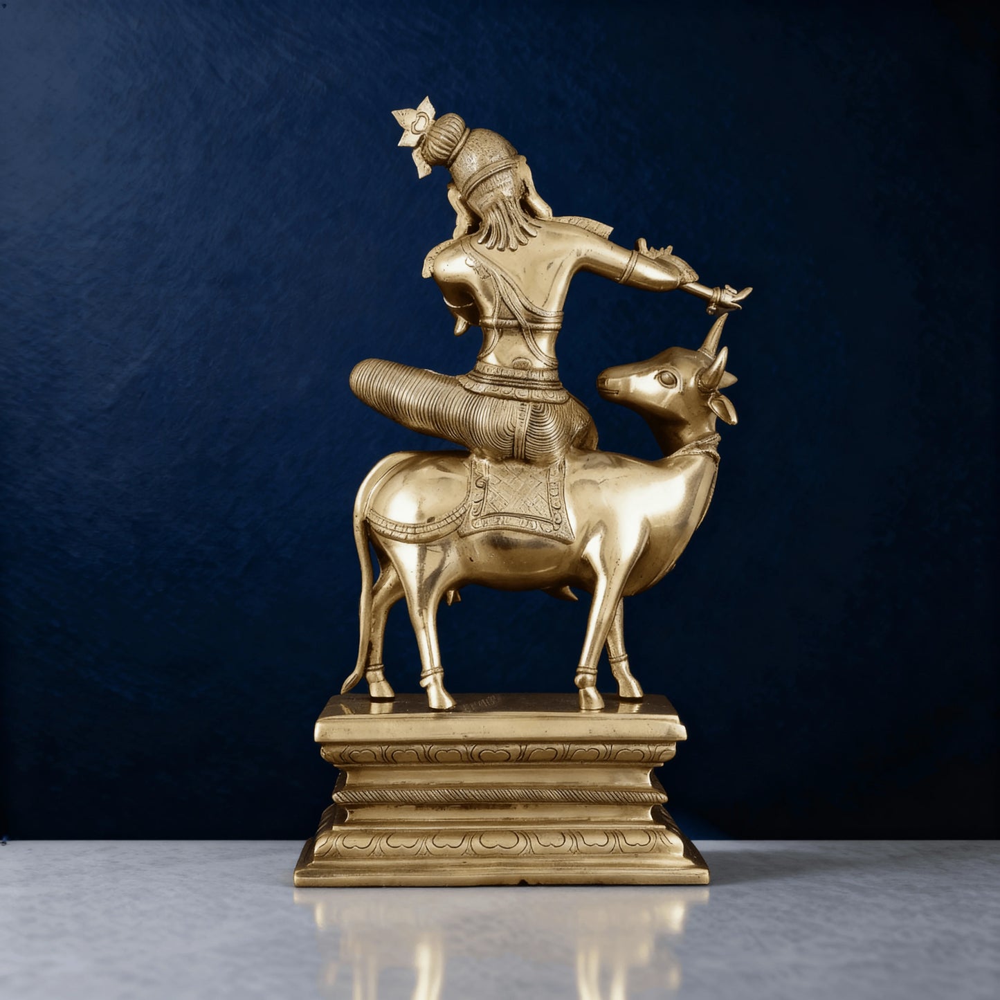 Rear view of Krishna brass statue riding cow, showing fine craftsmanship and detailed carvings, solid antique finish