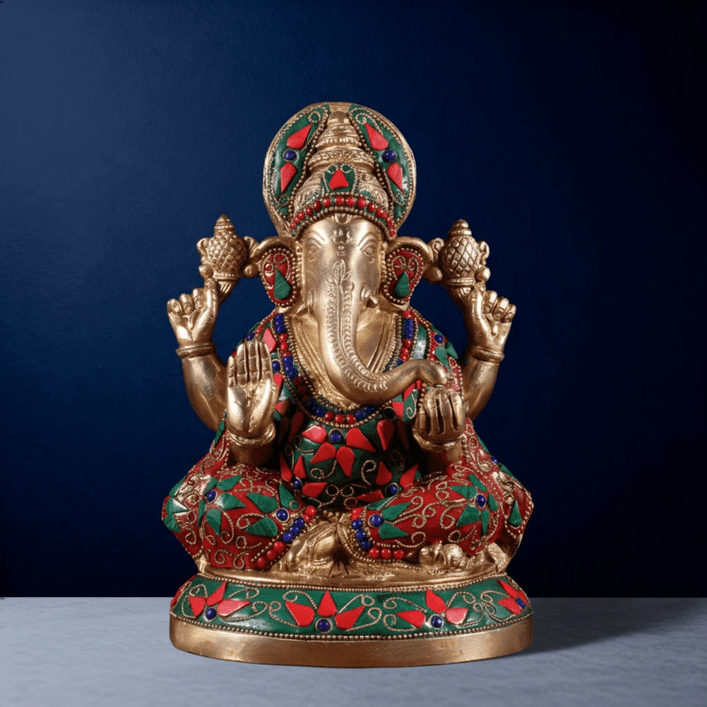 Front view of meenakari brass Ganesha idol with detailed red-green stone inlay, ornate crown, and traditional craftsmanship