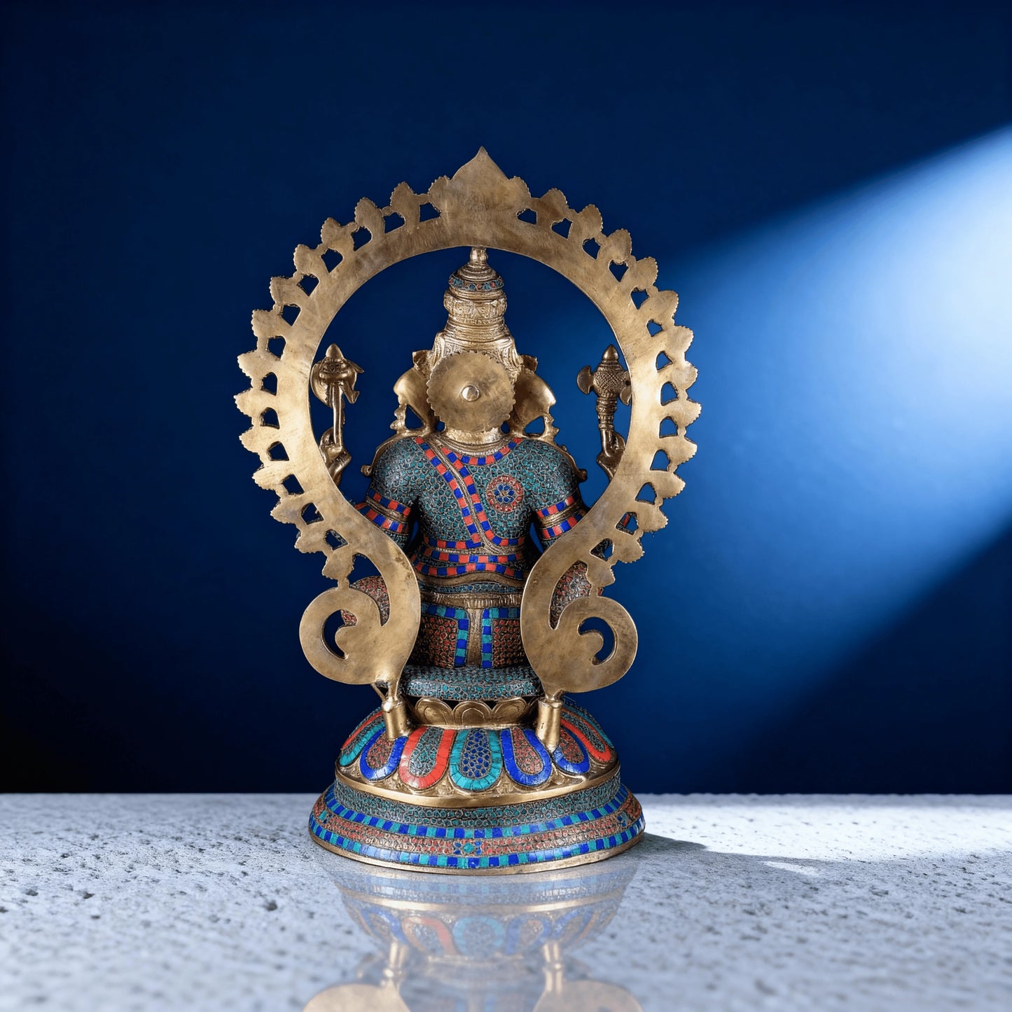 Back view of meenakari brass Ganesha statue showing detailed craftsmanship, stonework patterns, and decorative halo