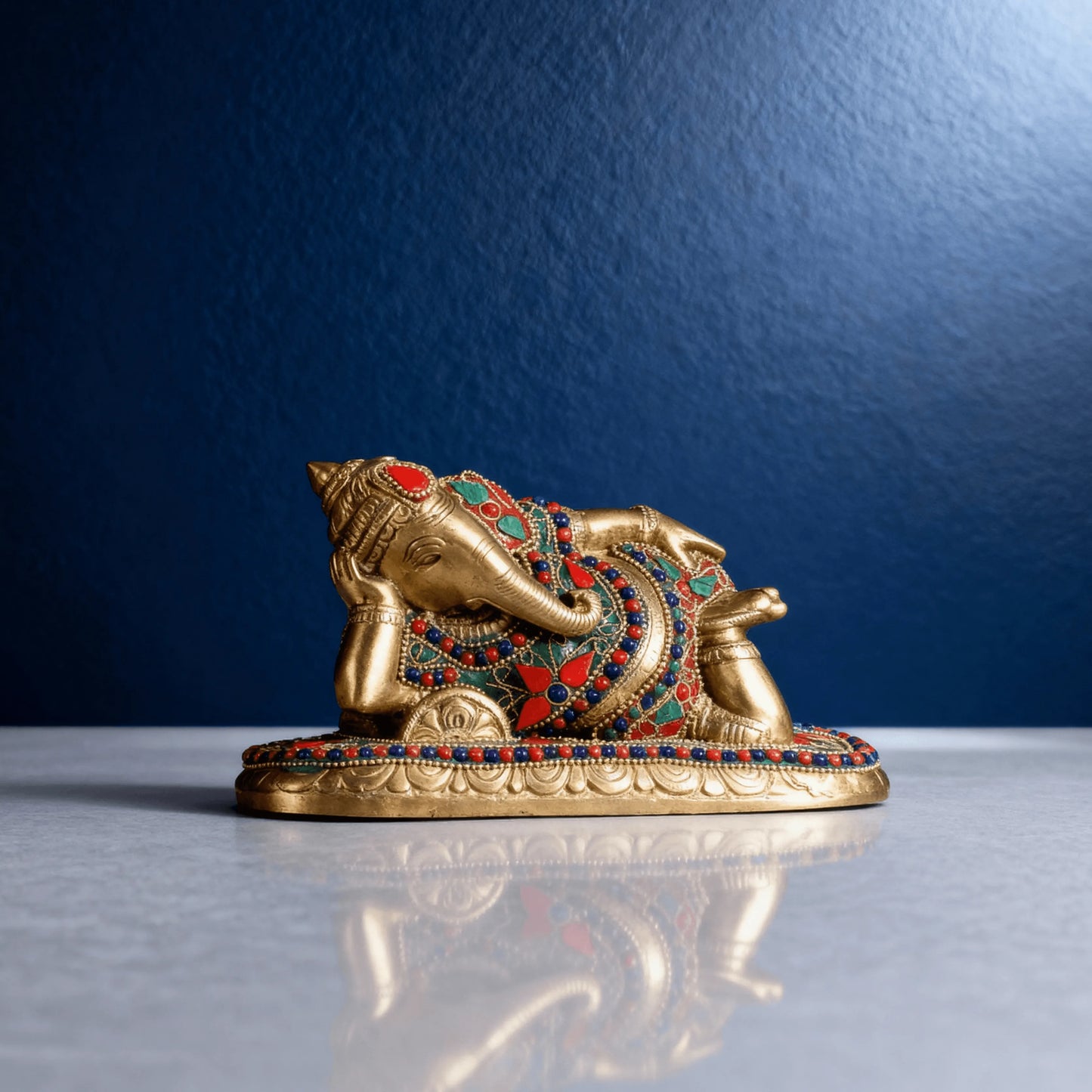 reclining brass ganesha statue with colorful stone work