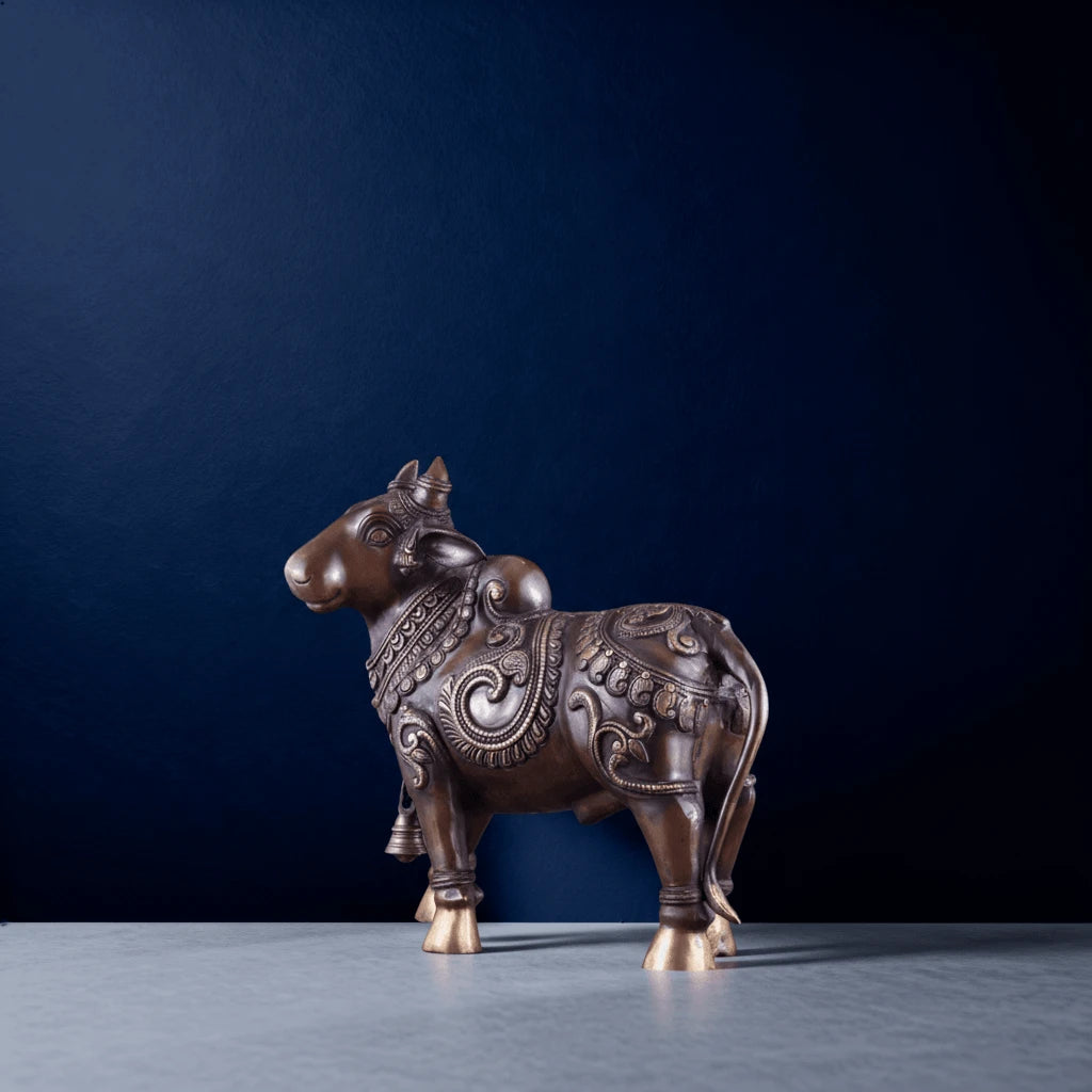 side profile of brass nandi statue standing on a smooth marble background