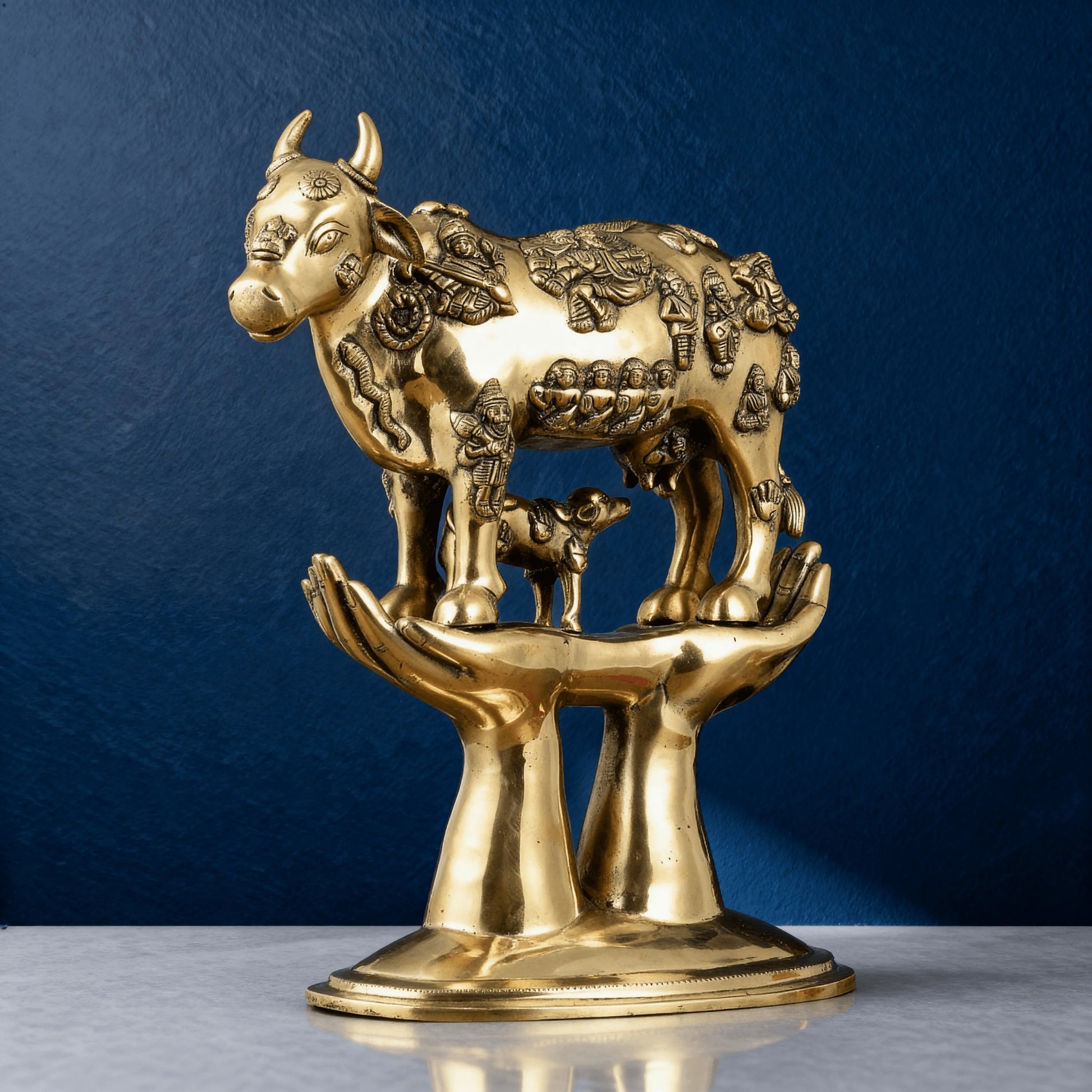 Handcrafted brass Kamadhenu cow idol with detailed carvings, standing on symbolic hands – Indian spiritual gift item